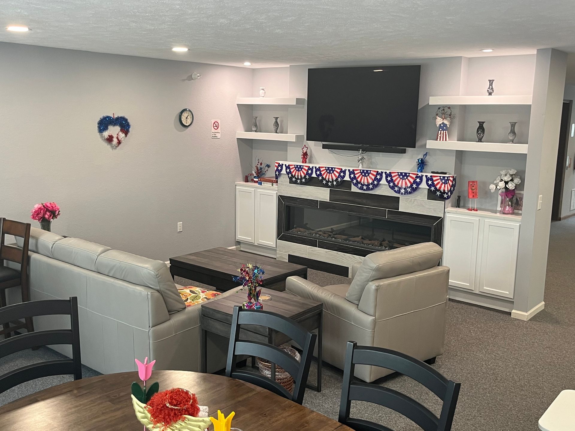 a living room with a couch , chairs , table and television .
