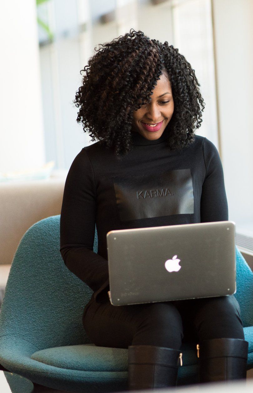 A woman is sitting in a chair using an apple laptop computer.