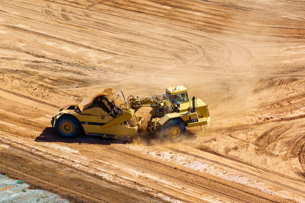 A yellow bulldozer is driving through a dirt field