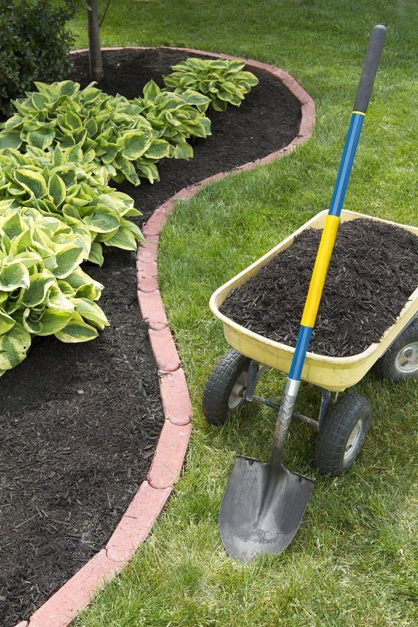 flower bed with fresh mulch with a dump cart full of mulch ready to be dumped