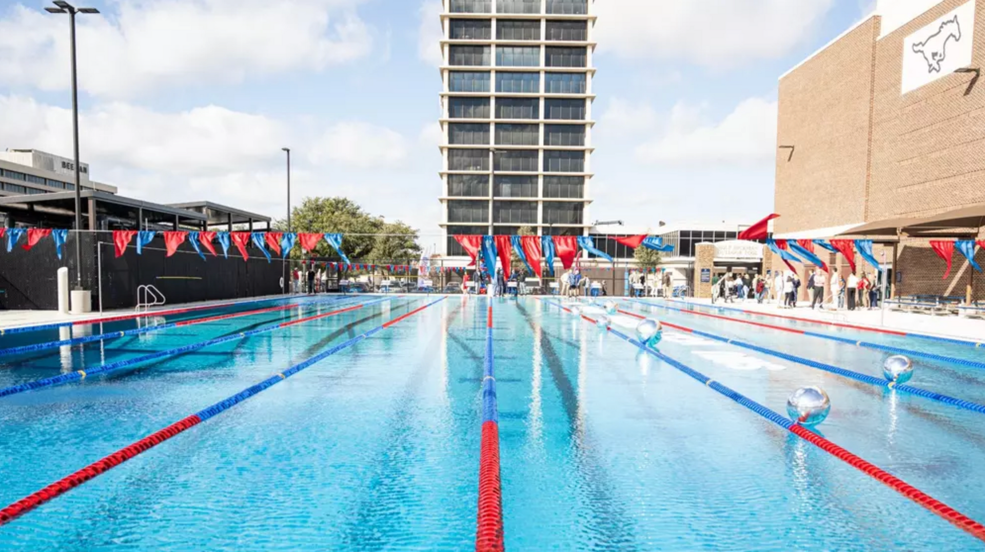 A large swimming pool with a tall building in the background.