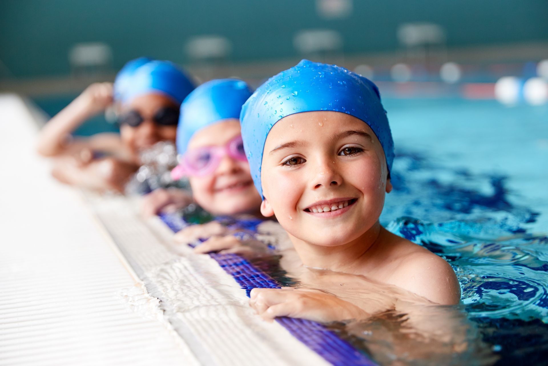 A group of young children are swimming in a swimming pool.