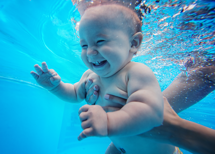 A baby is swimming underwater in a pool.