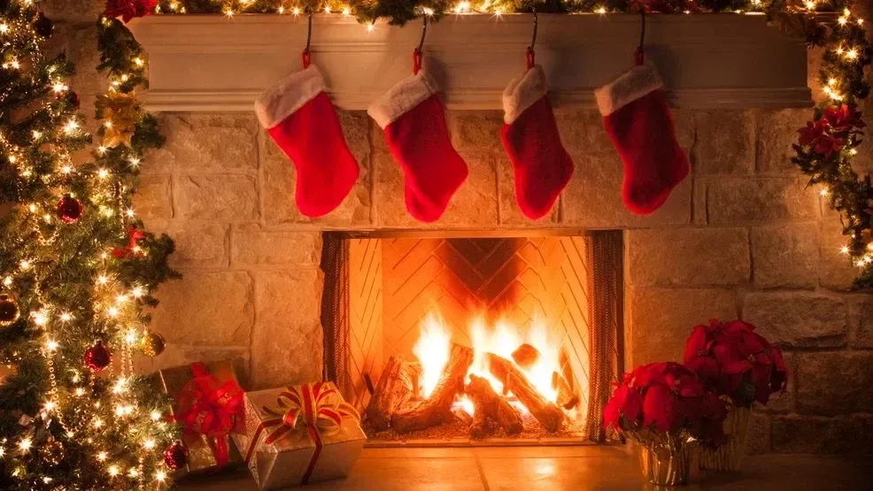 Fireplace with stockings and Christmas decorations: burning fire, red stockings, and festive lights.