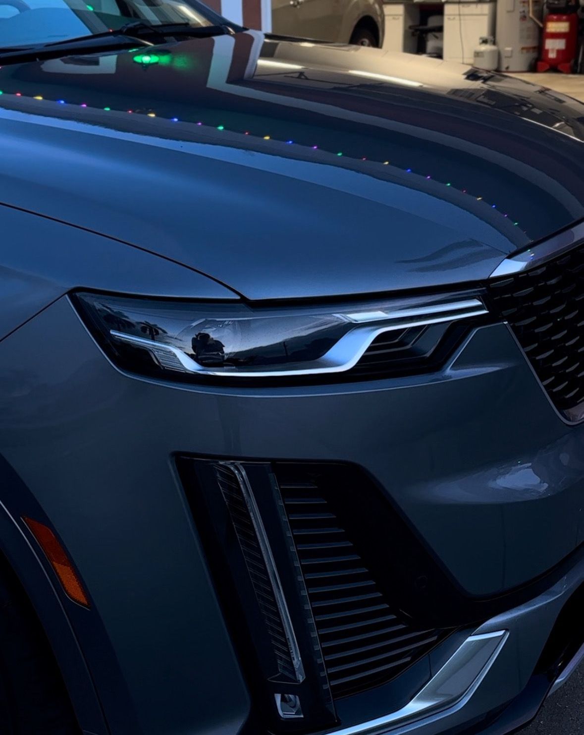 Dark gray Cadillac SUV headlight and grille.