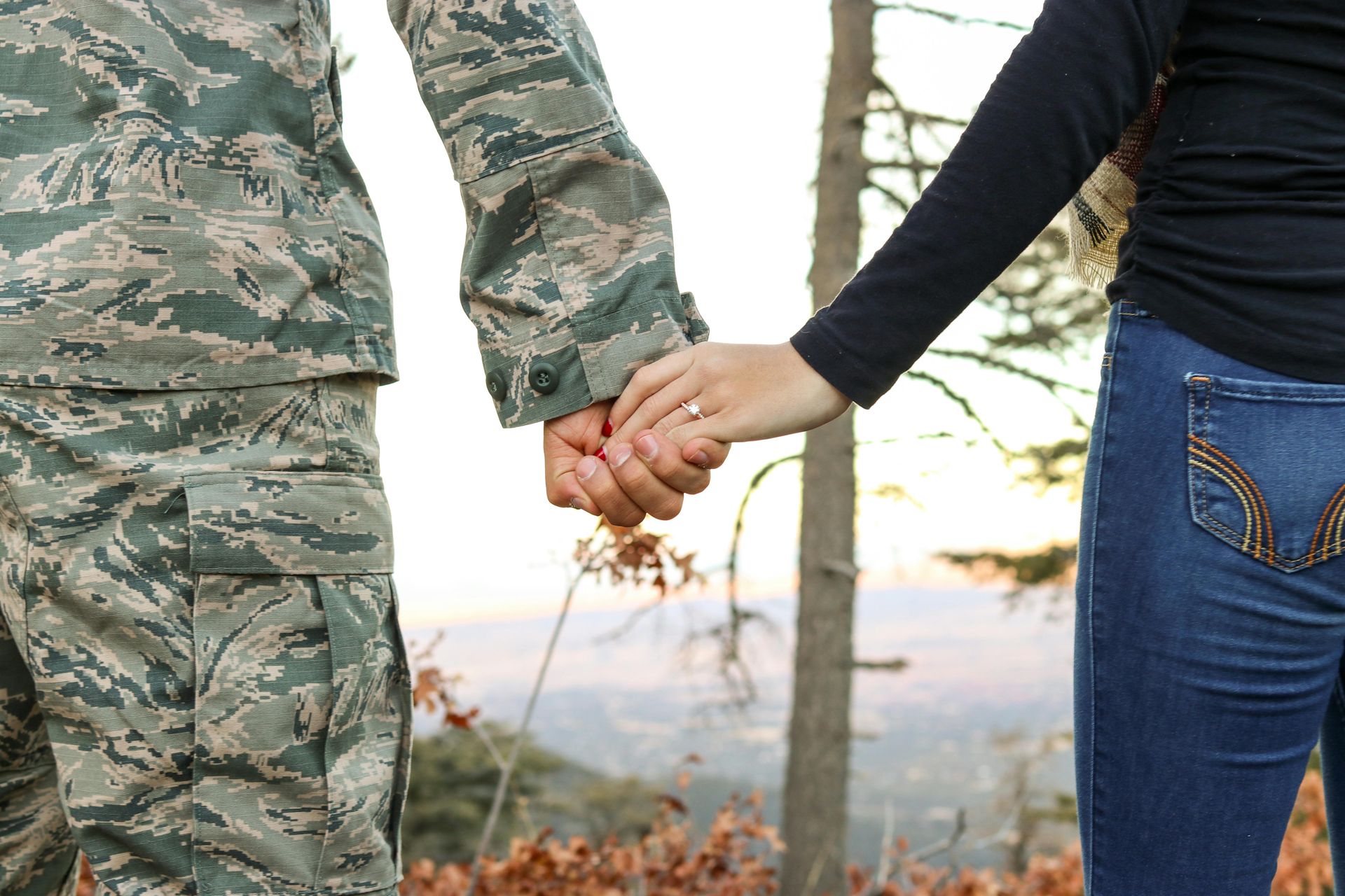 A man in a military uniform is holding a woman 's hand.