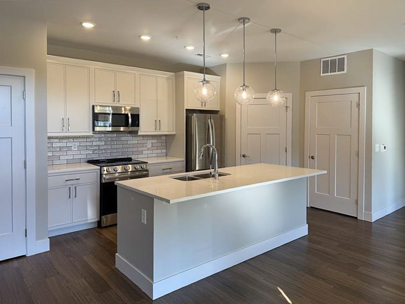Modern kitchen with white cabinets, island, and stainless steel appliances.
