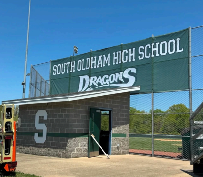 South Oldham High School Dragons stadium entrance with green sign and brick wall under clear blue sky