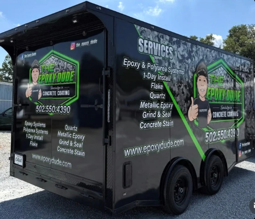 Black service trailer with green lettering for repair and hauling services, parked outdoors.