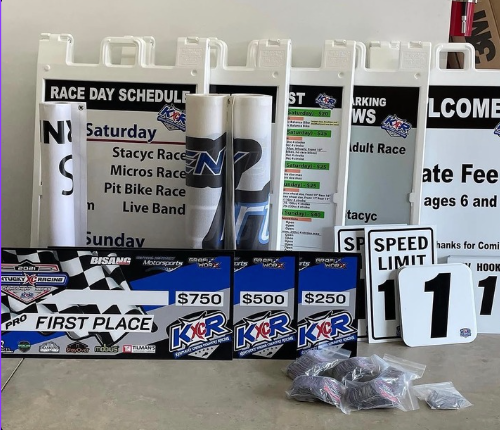 Raceday event signboard with schedule, race awards, speed limit numbers, and prize plaques on display