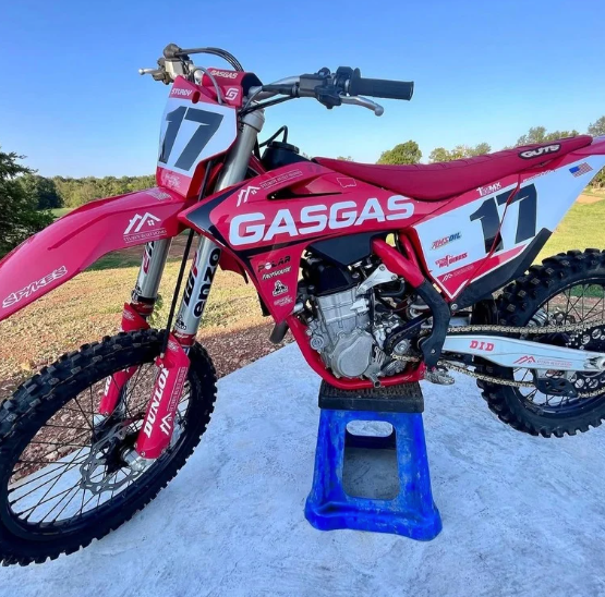 Red GasGas dirt bike with number 17 on a blue stand outdoors under a clear sky