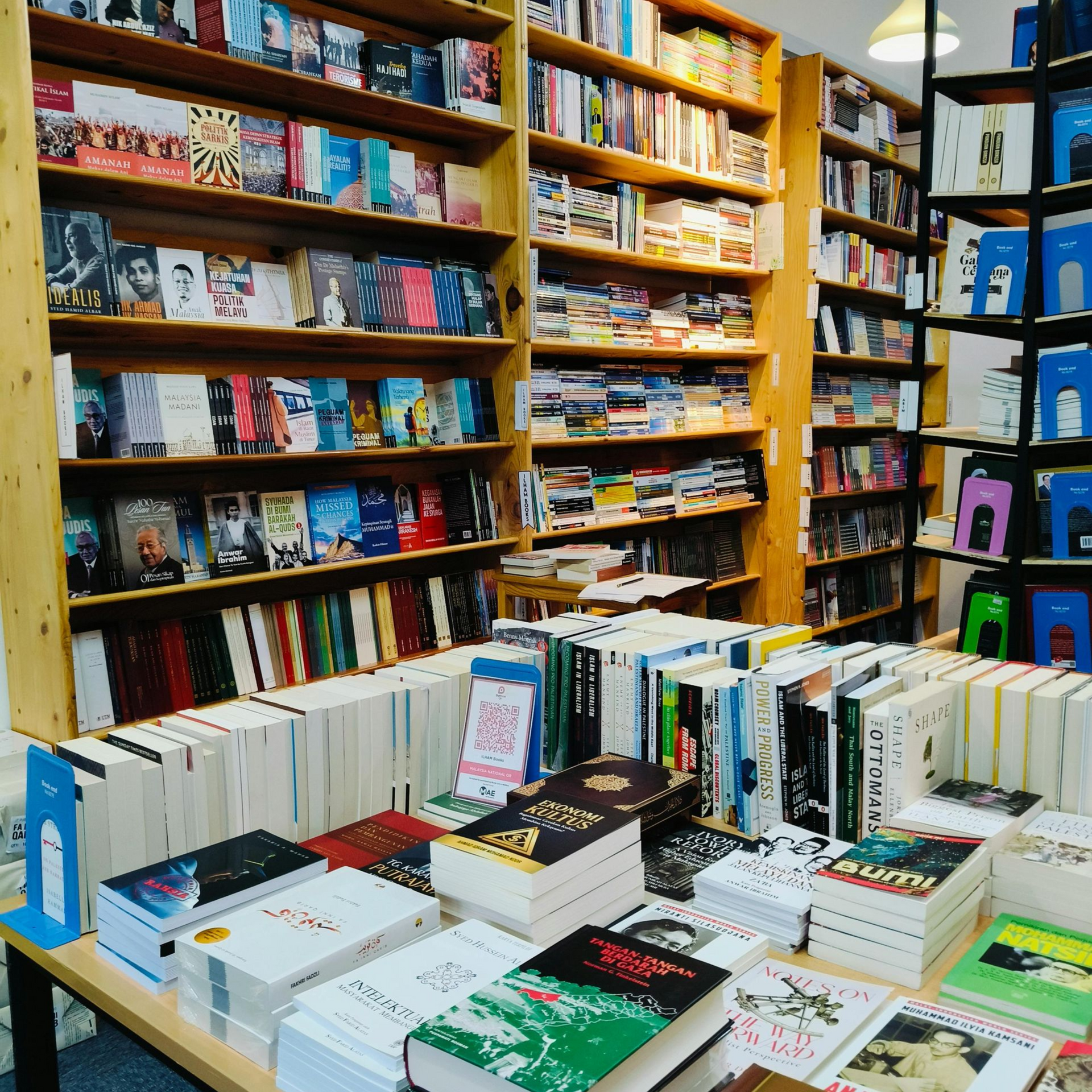 De schappen van een boekwinkel en een presentatietafel vol kleurrijke boeken en tijdschriften.