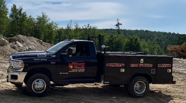 A large rock formation in the middle of a quarry with a crane in the background.