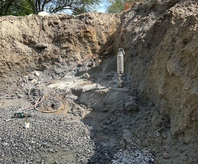 A large pile of dirt is being blown up in the middle of a forest
