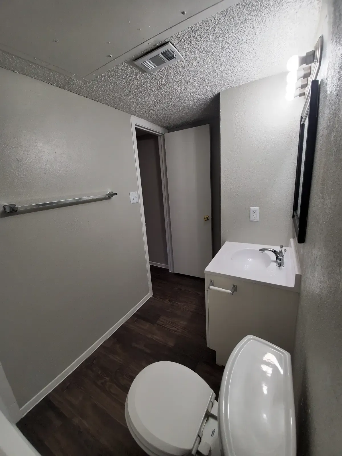 A bathroom with a toilet , sink and mirror.
