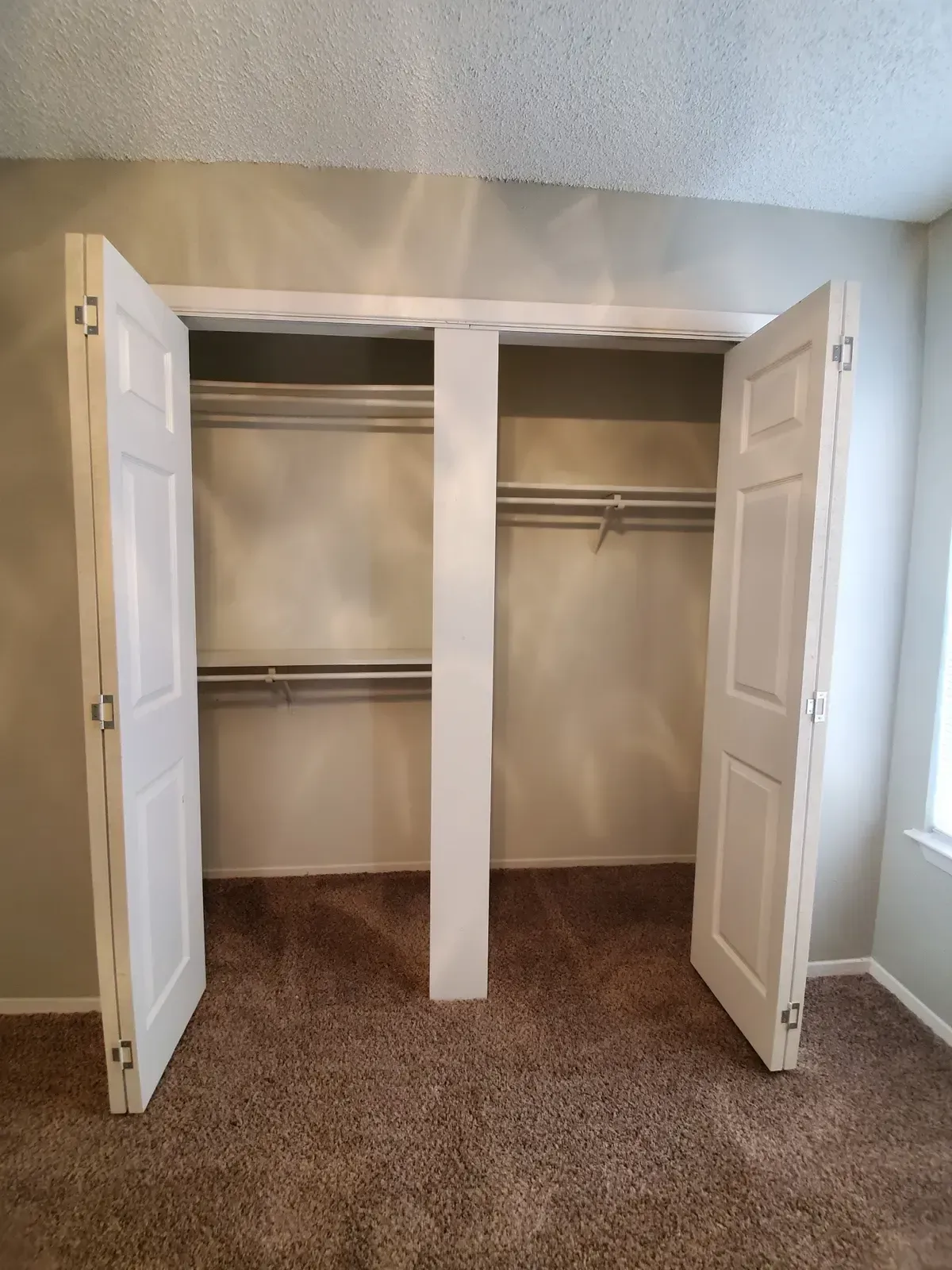 An empty closet with the doors open in a bedroom