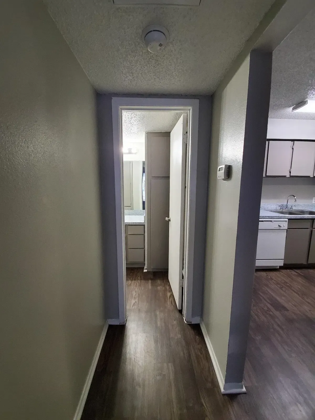 A hallway leading to a kitchen and bathroom in a house.