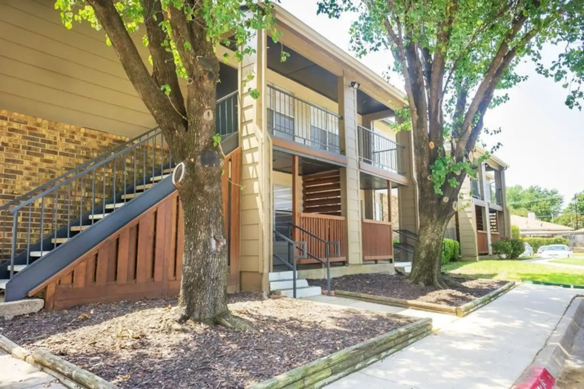 A large apartment building with stairs and trees in front of it.