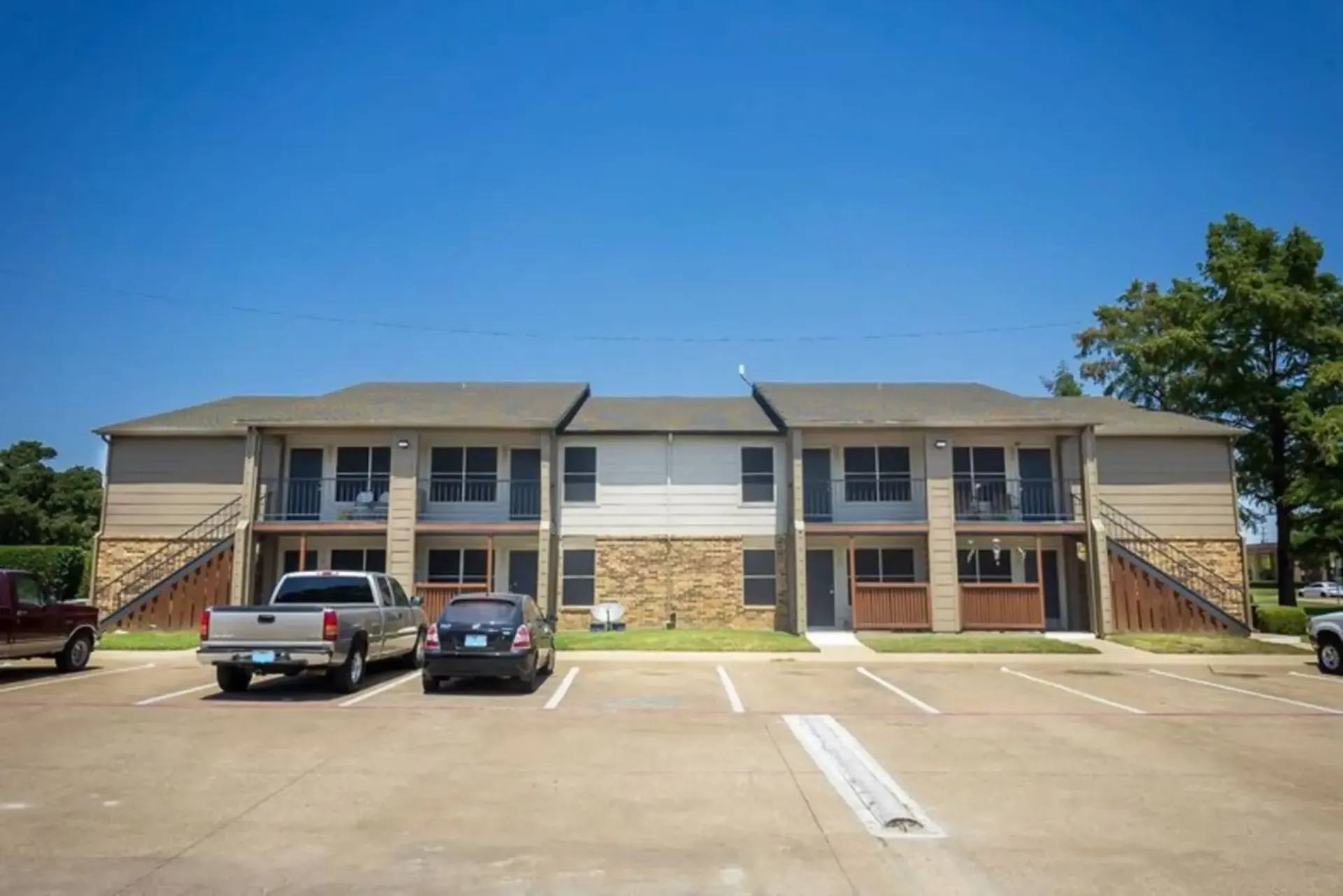 A large apartment building with cars parked in front of it.