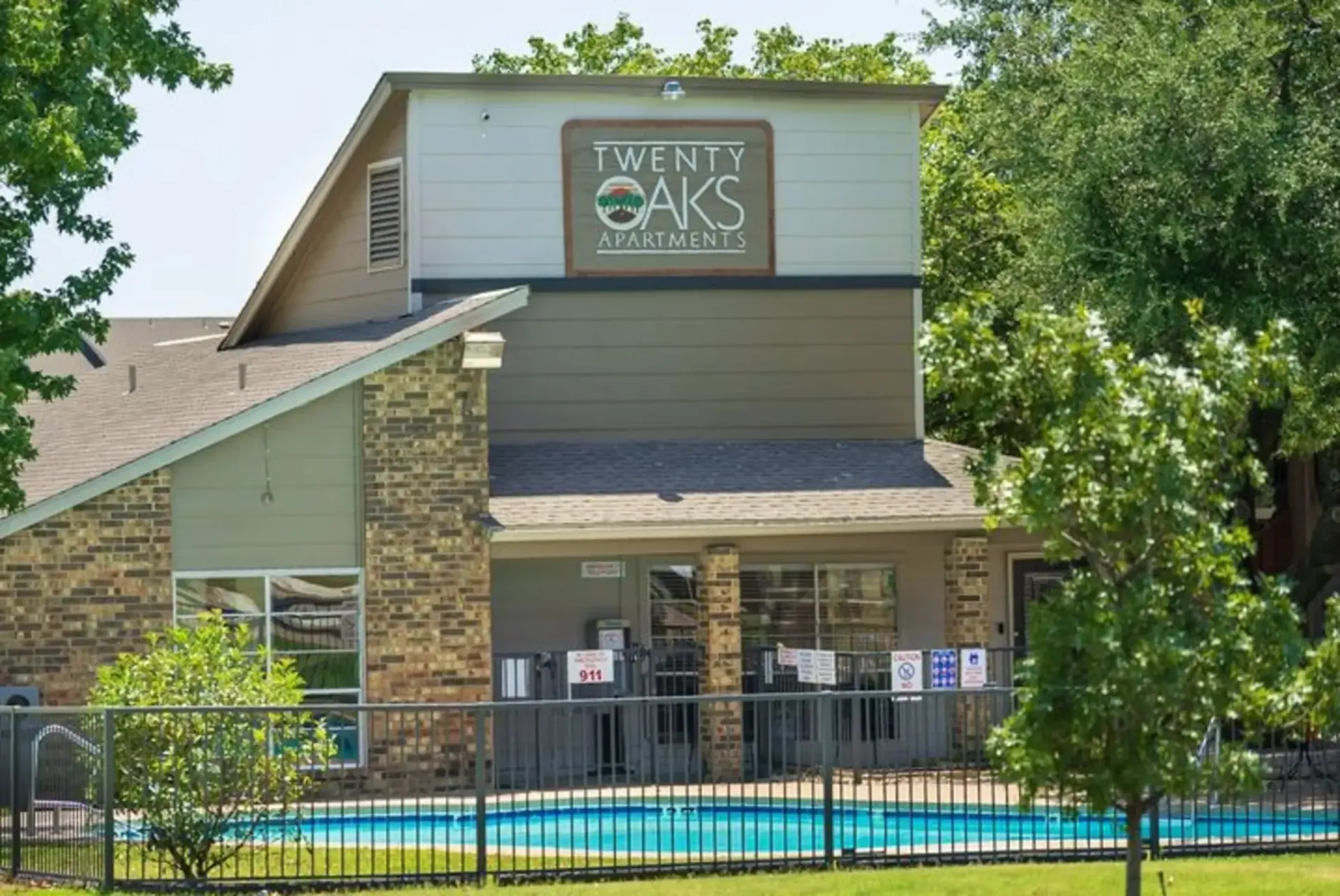 A building with a pool in front of it and a sign that says twenty oaks