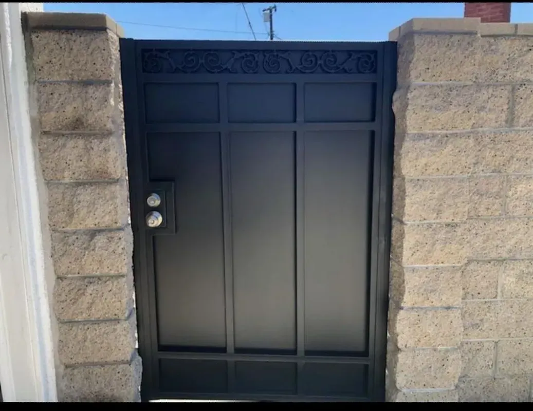 Black metal gate set between stone brick pillars.