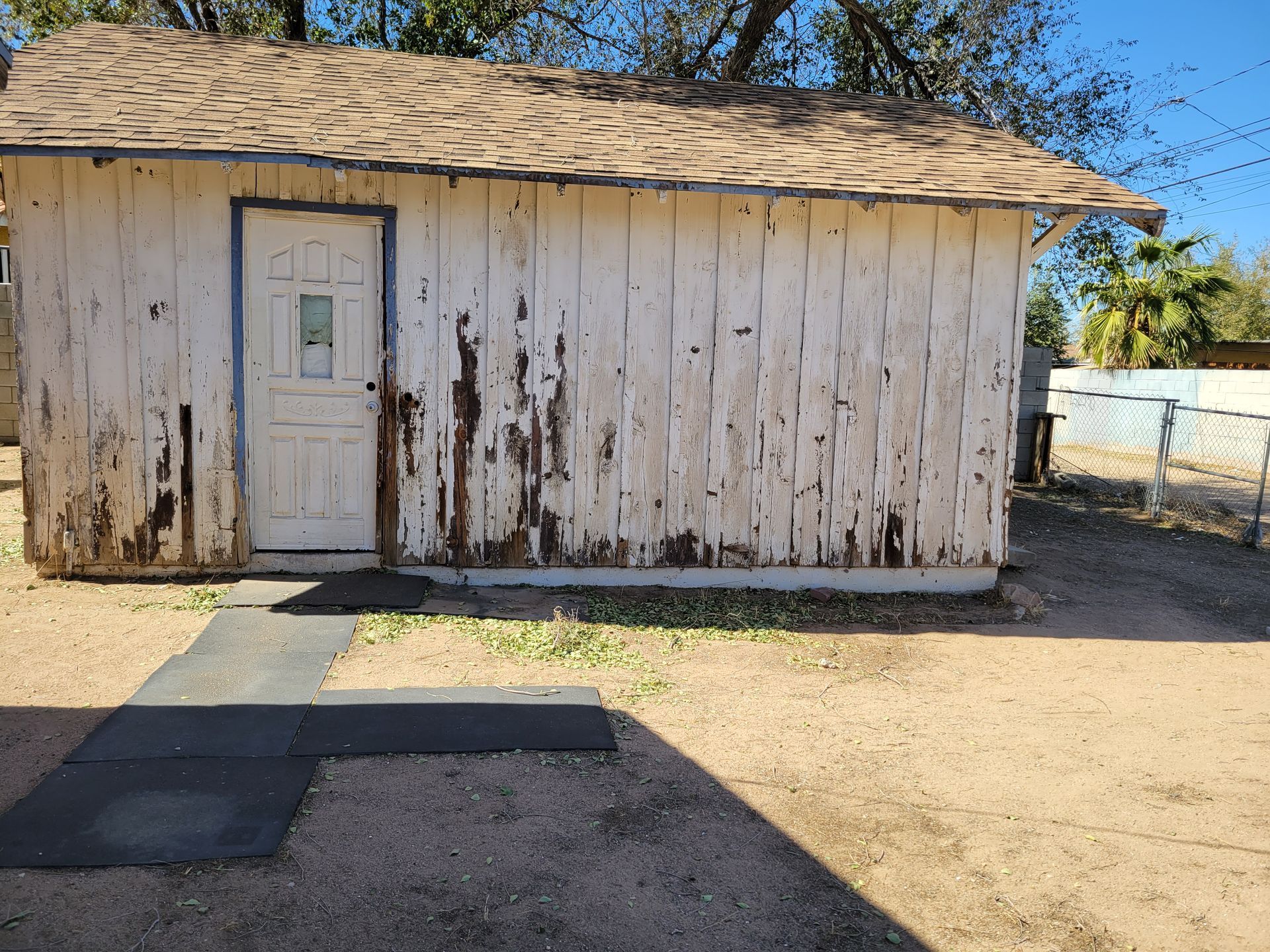 A small white shed with a brown roof and a door.