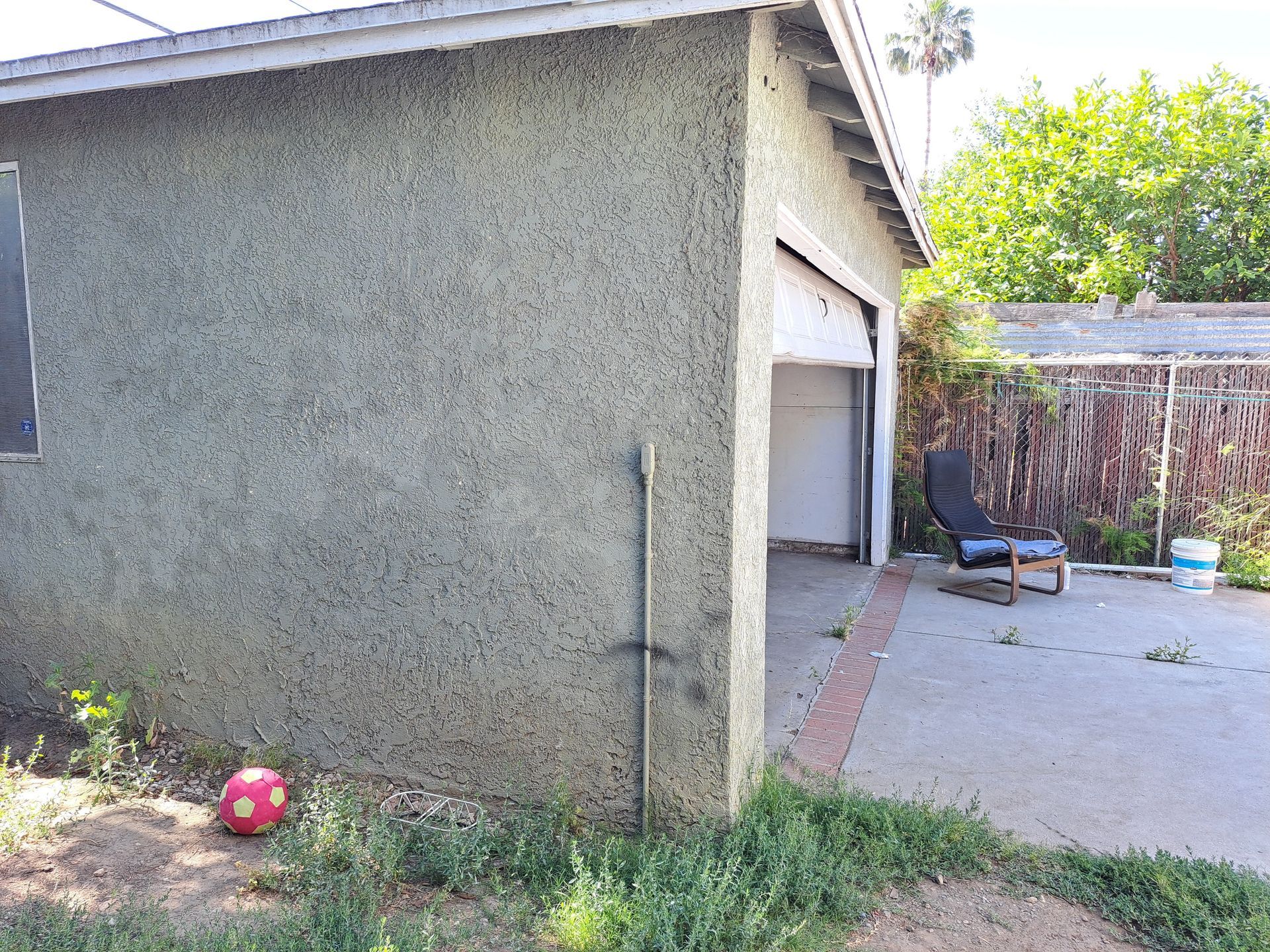 A garage with a chair and a soccer ball in front of it.