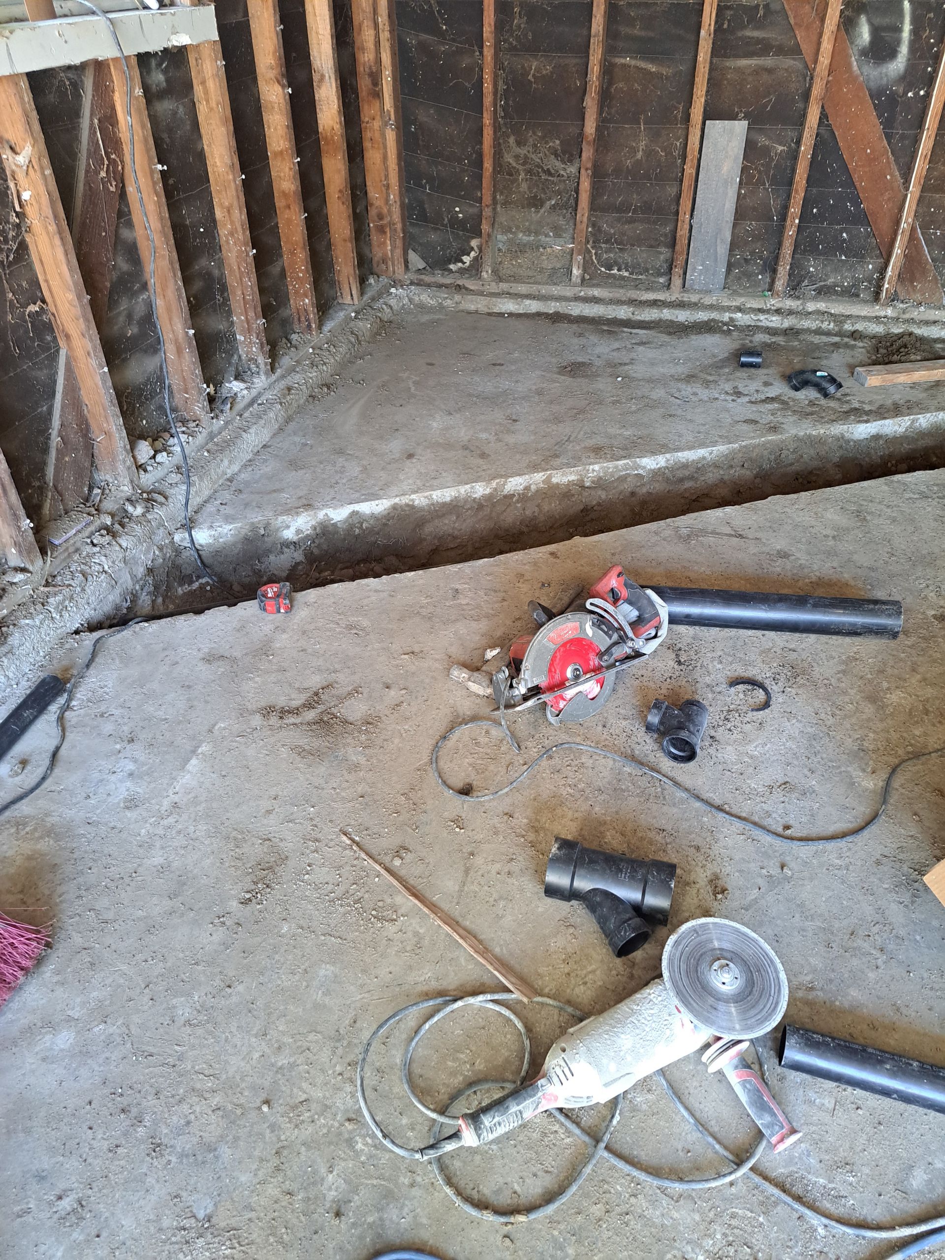 A circular saw and a grinder are sitting on the floor of a room.