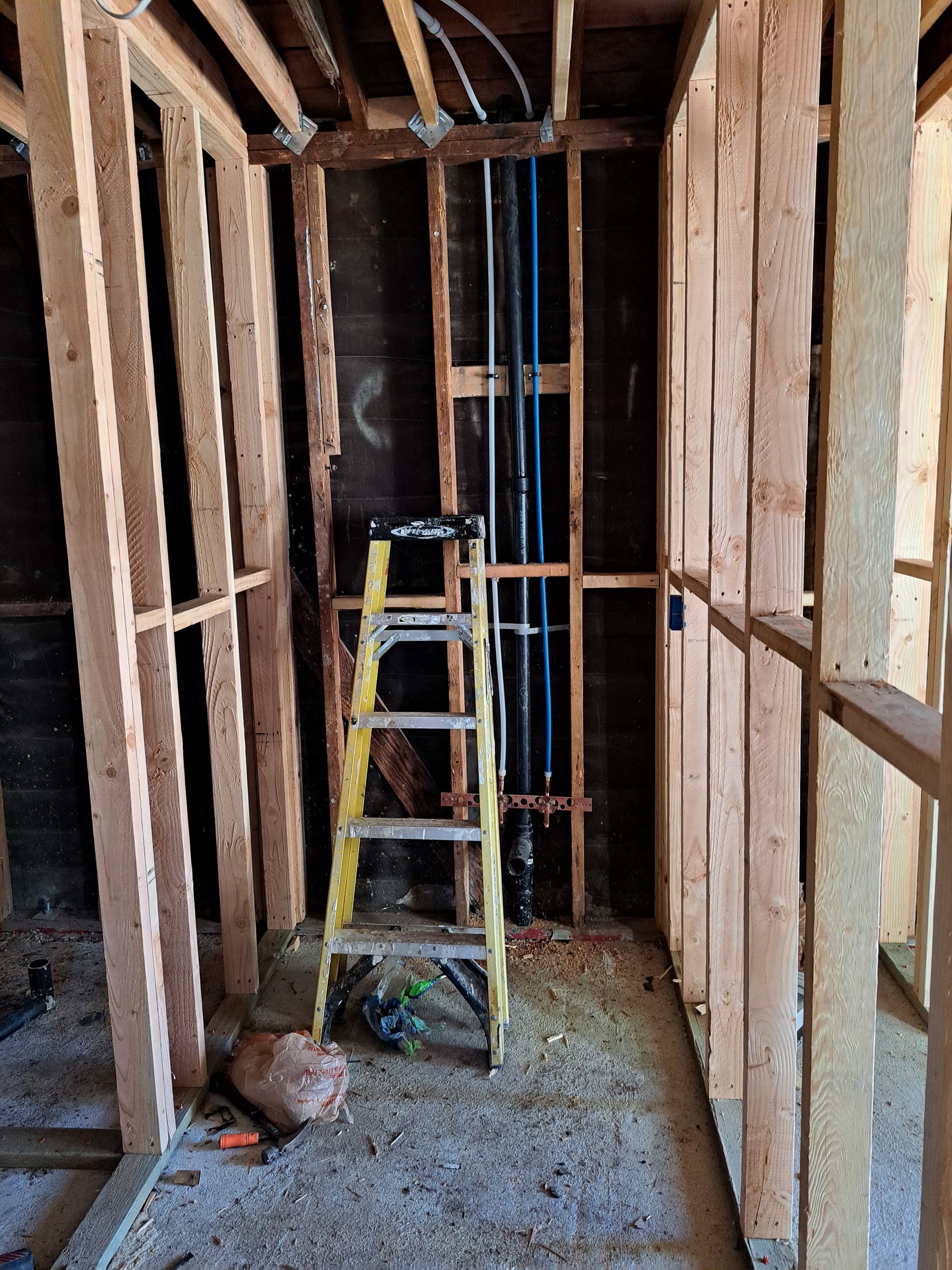 A ladder is sitting in the middle of a room in a house under construction.
