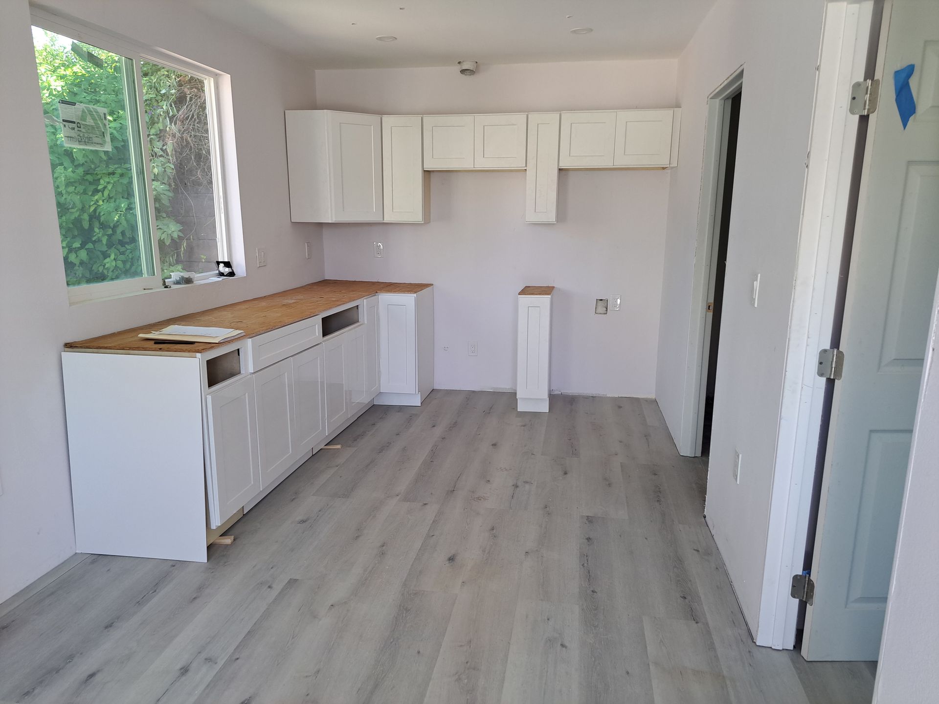 An empty kitchen with white cabinets and a wooden counter top.