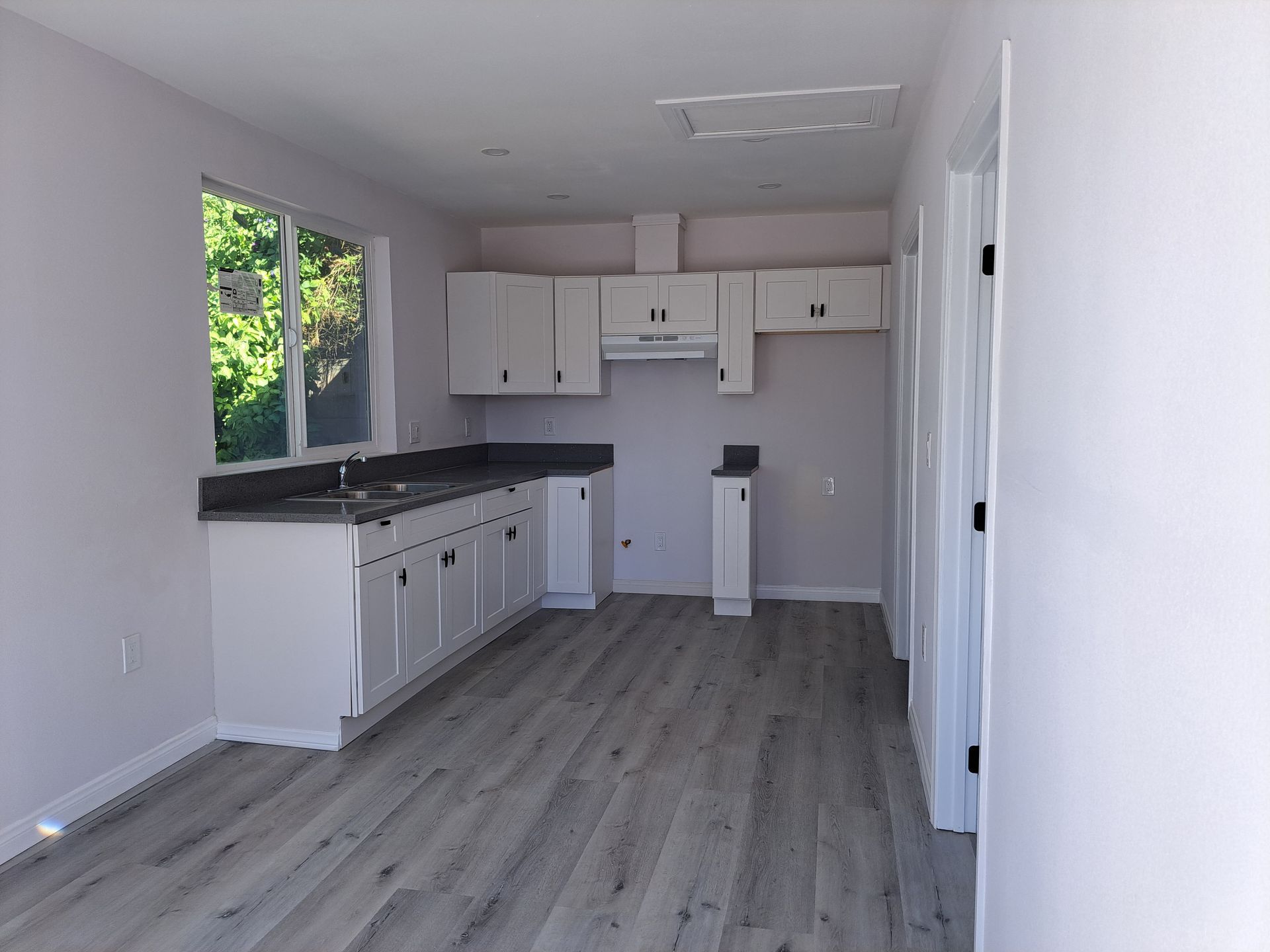 An empty kitchen with white cabinets and hardwood floors