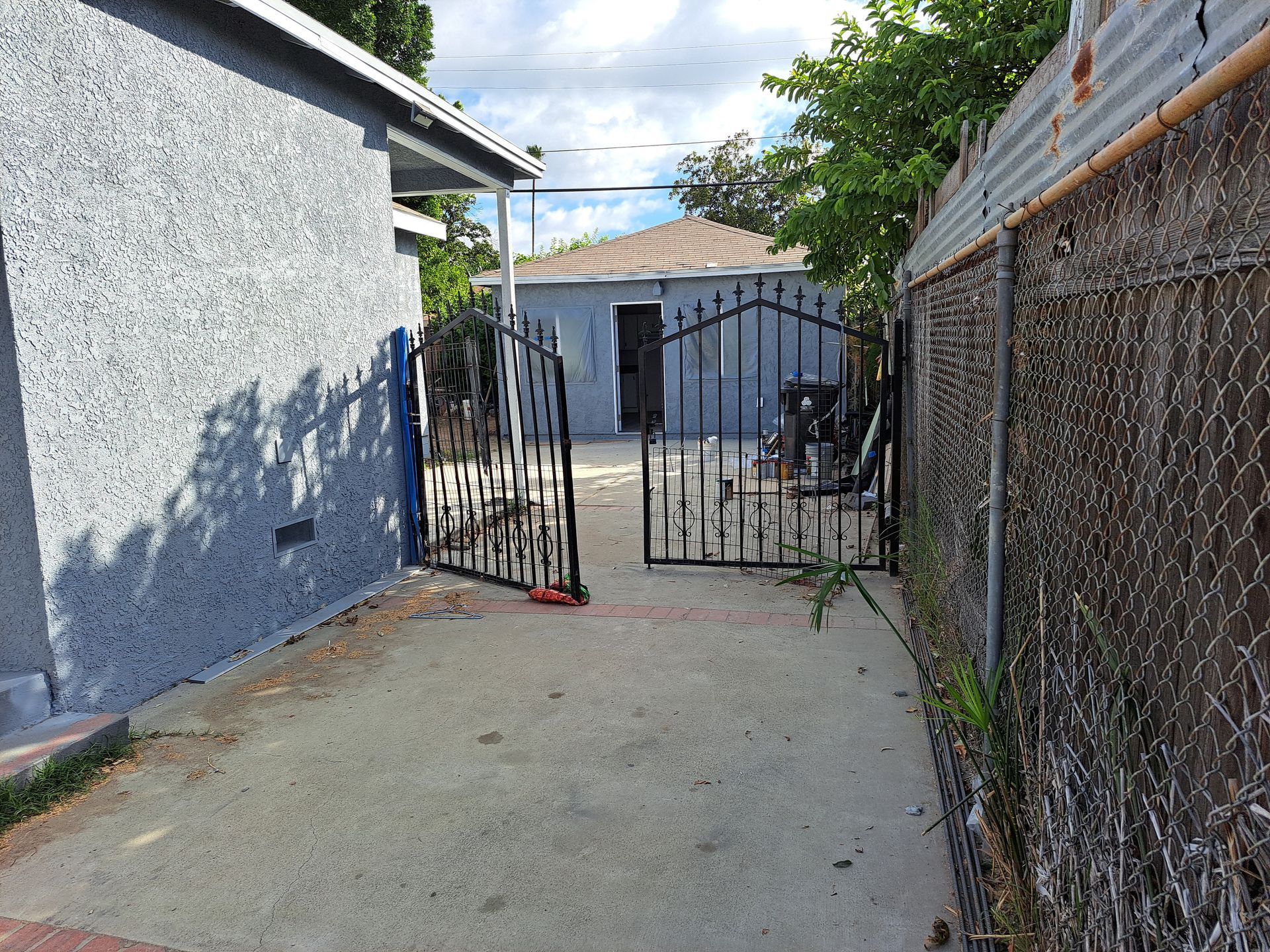 A broken gate in a driveway leading to a house