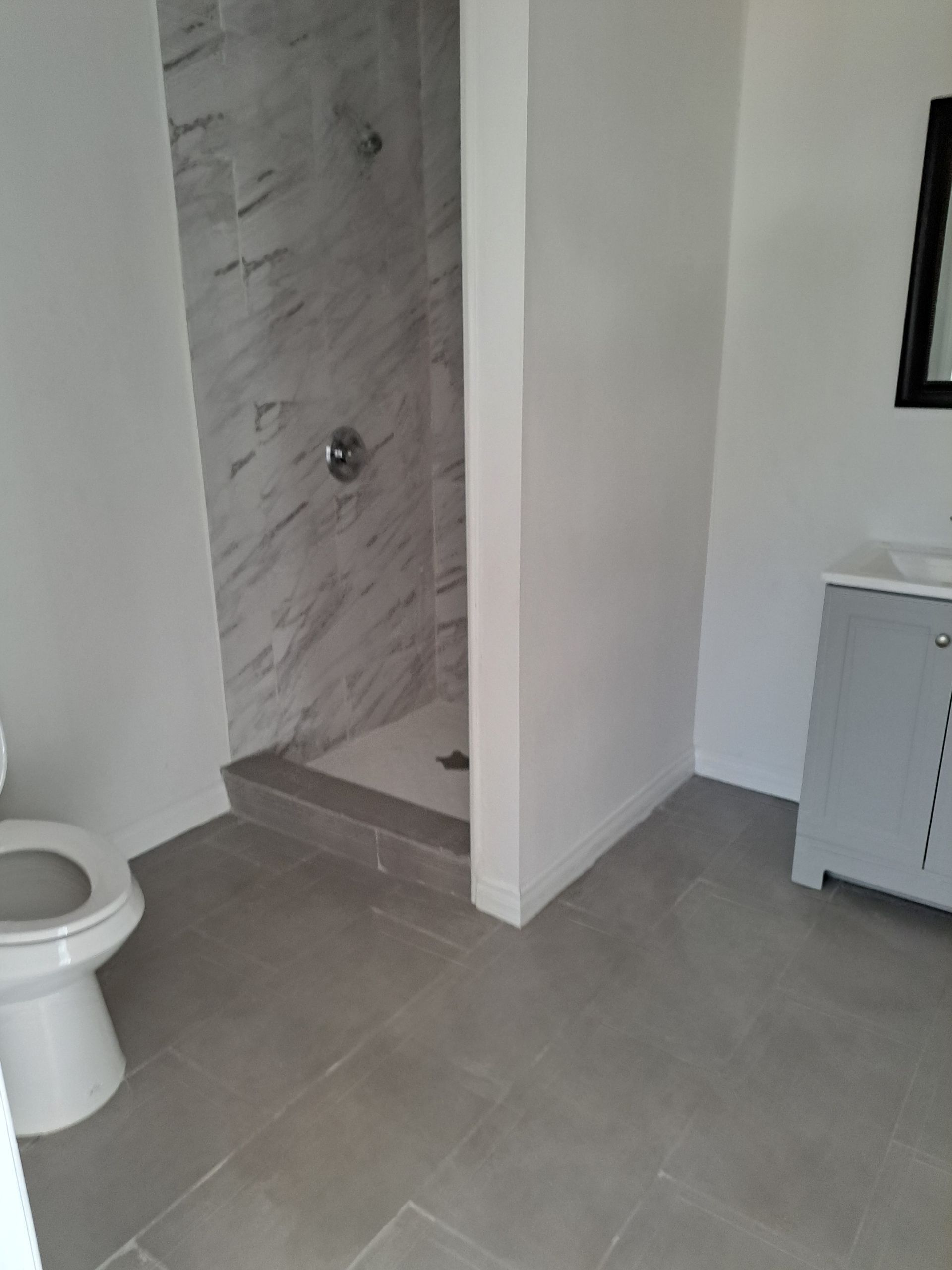 A bathroom with a toilet , sink and shower.