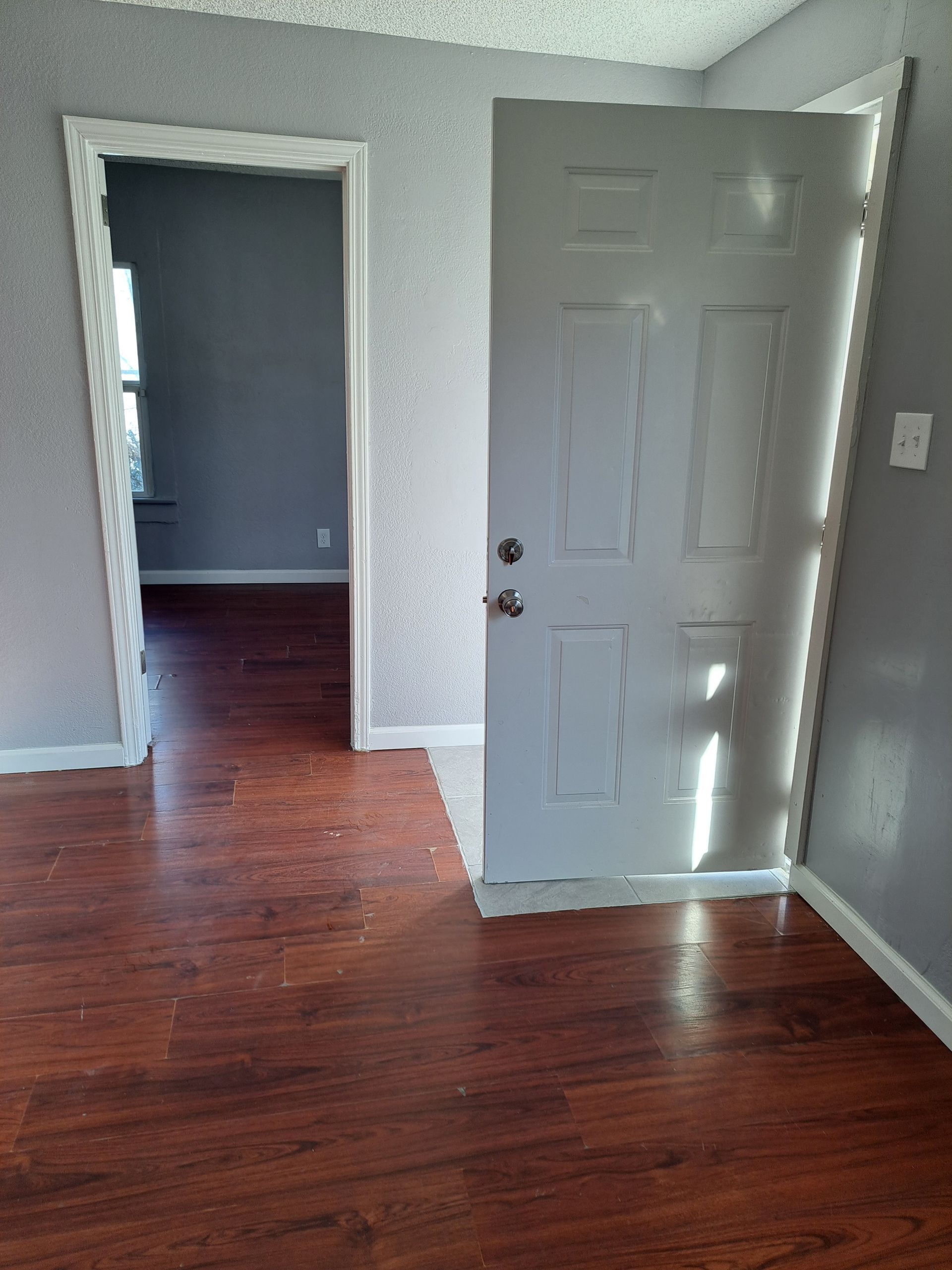 An empty room with hardwood floors and a white door.