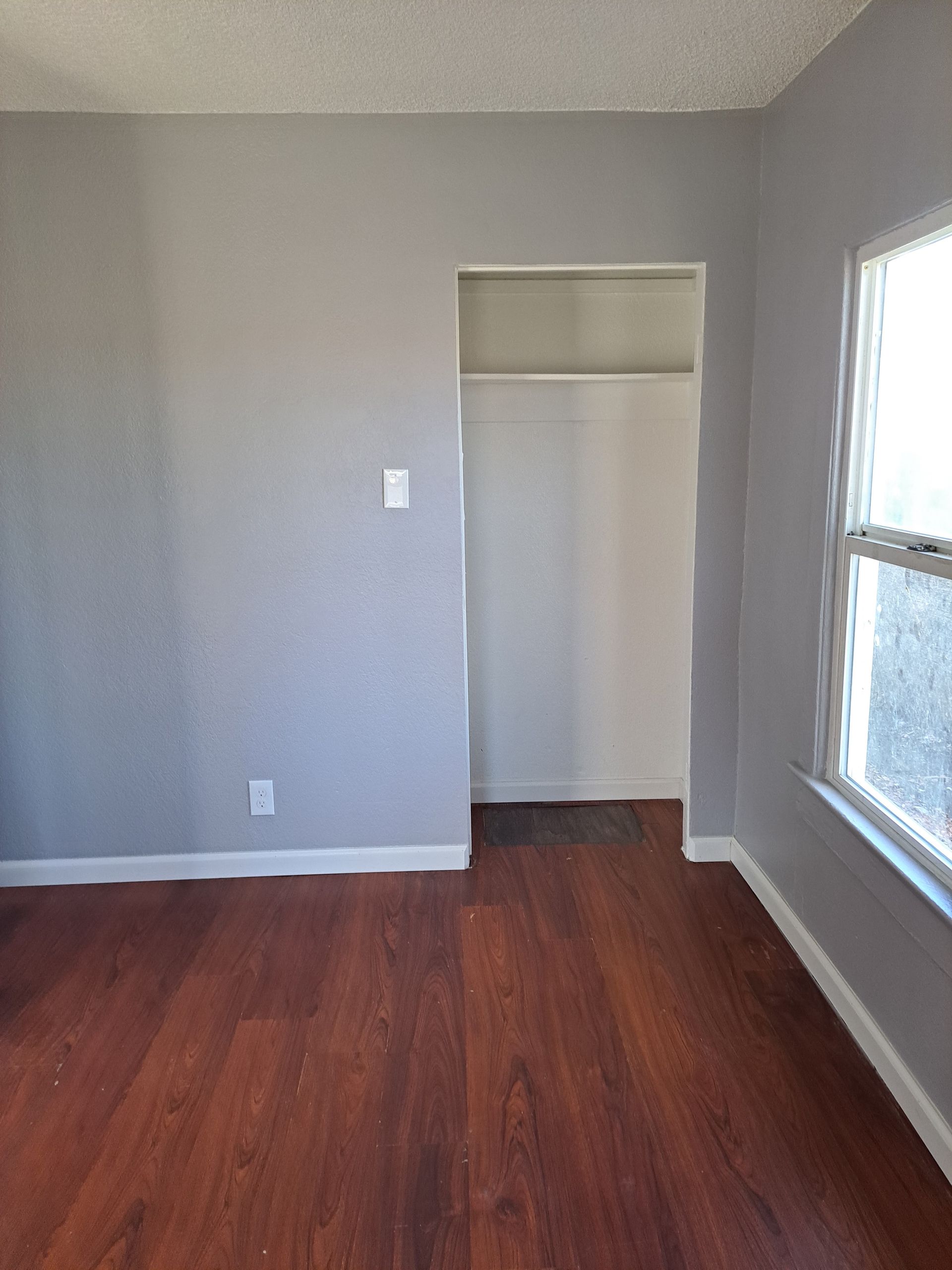 An empty room with hardwood floors and a window.