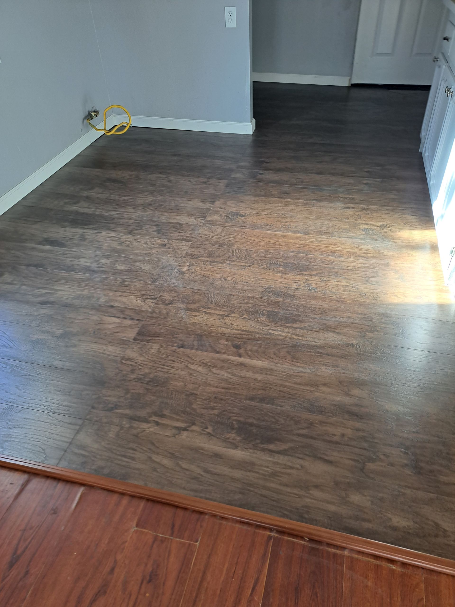 A room with hardwood floors and a yellow tape measure on the floor.