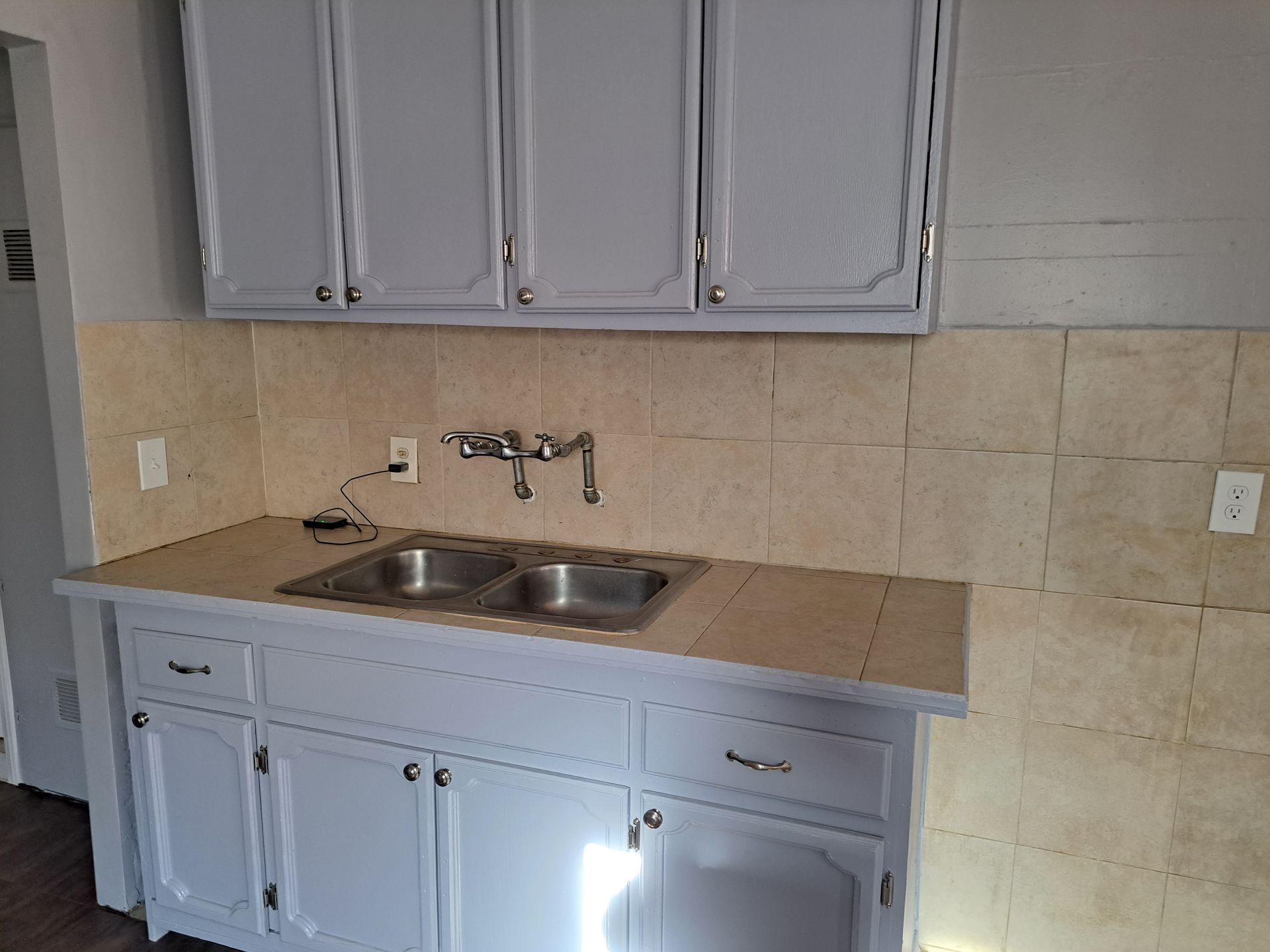 A kitchen with gray cabinets and a sink.