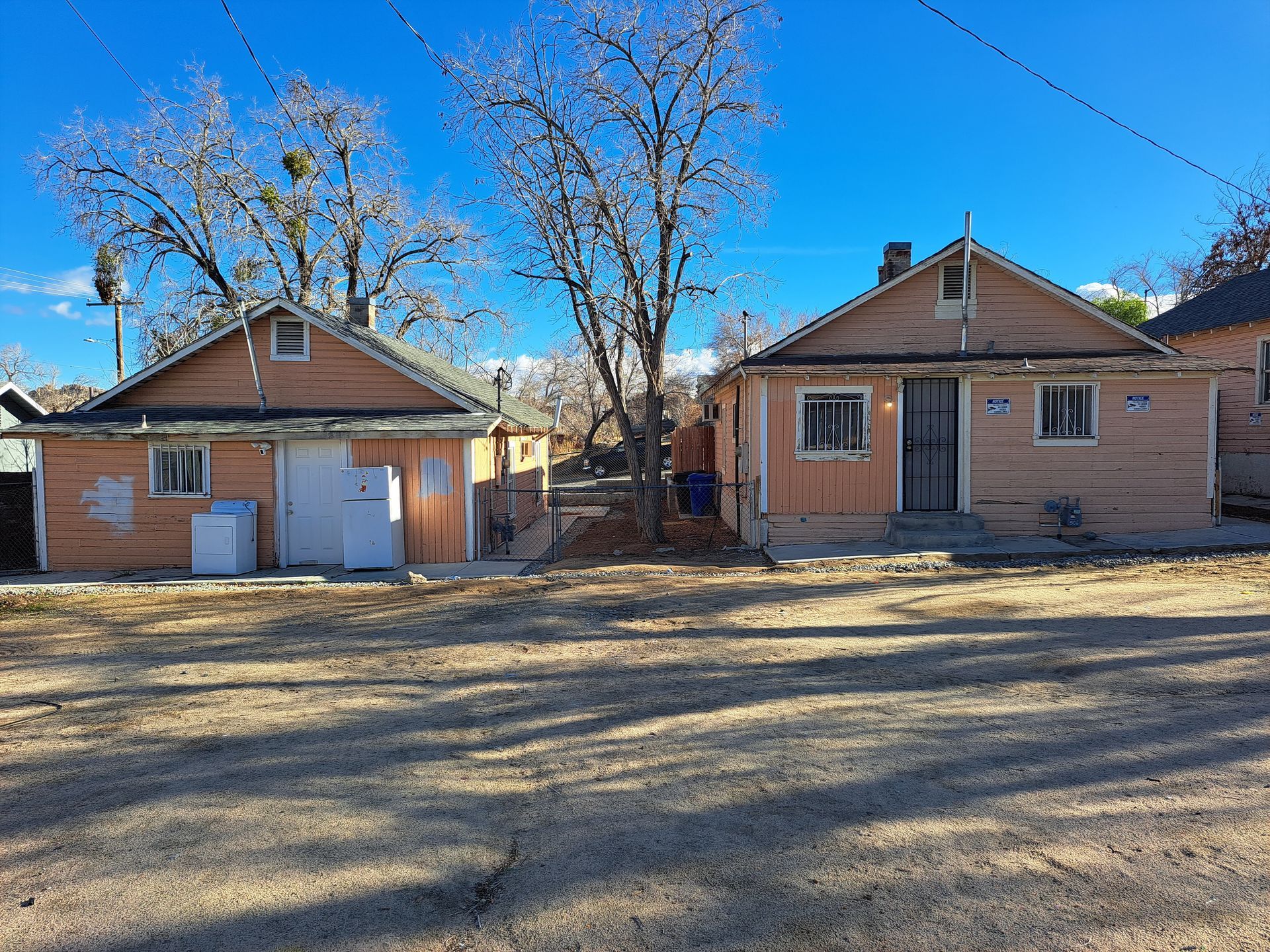 A couple of houses are sitting next to each other on a dirt road.