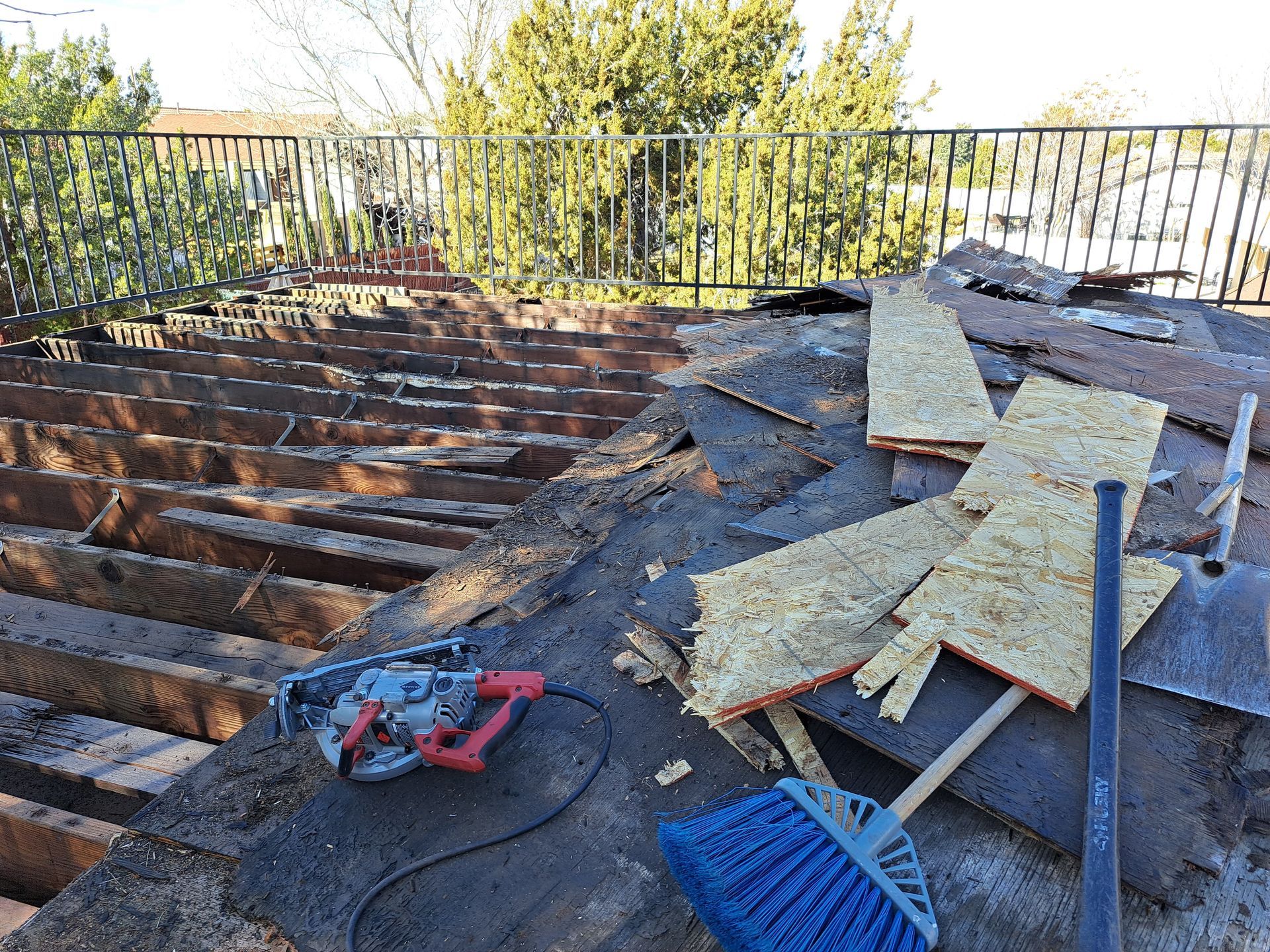 A broom and a saw are sitting on top of a roof.