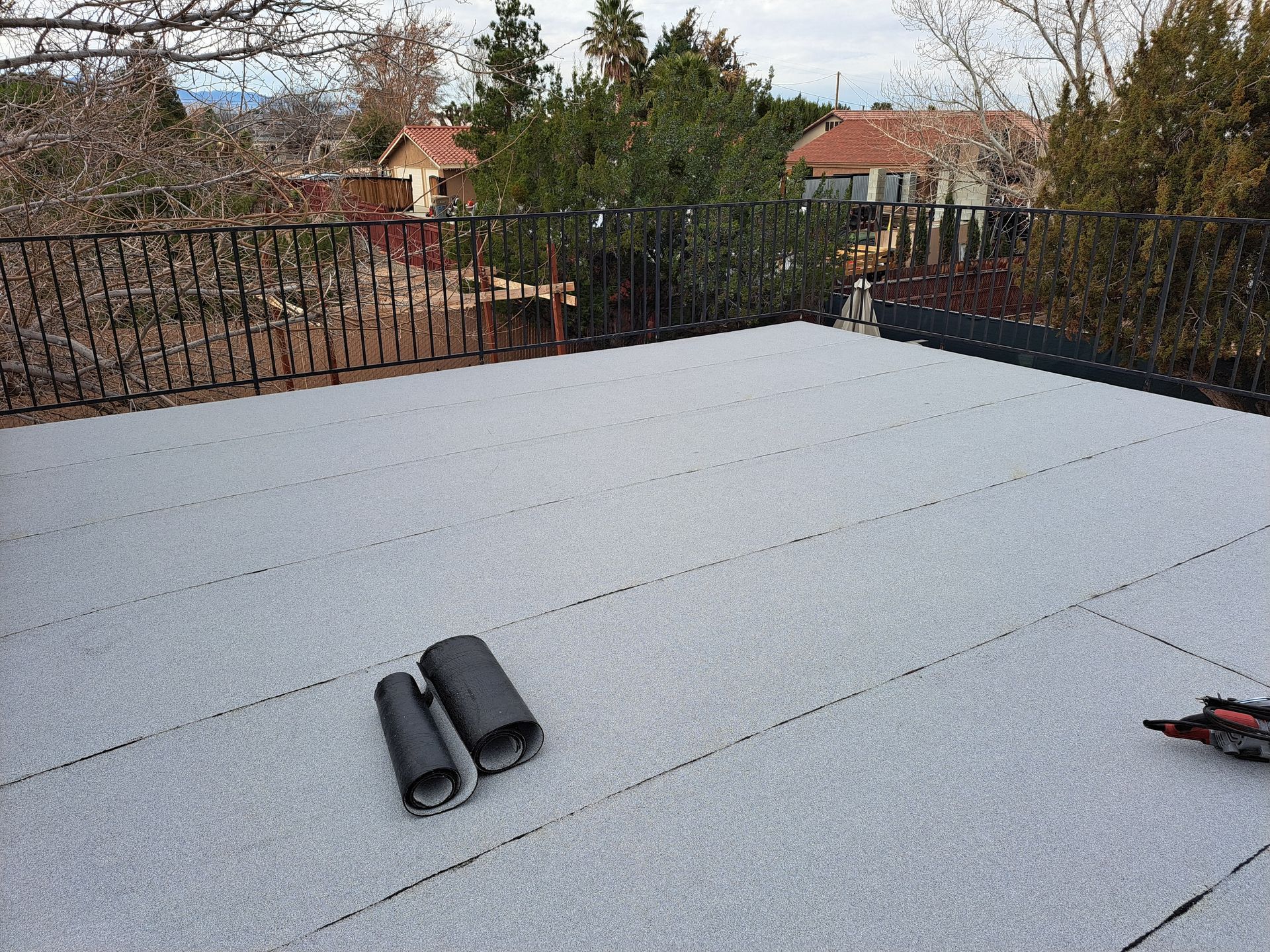 A roof with a few rolls of roofing material on it.