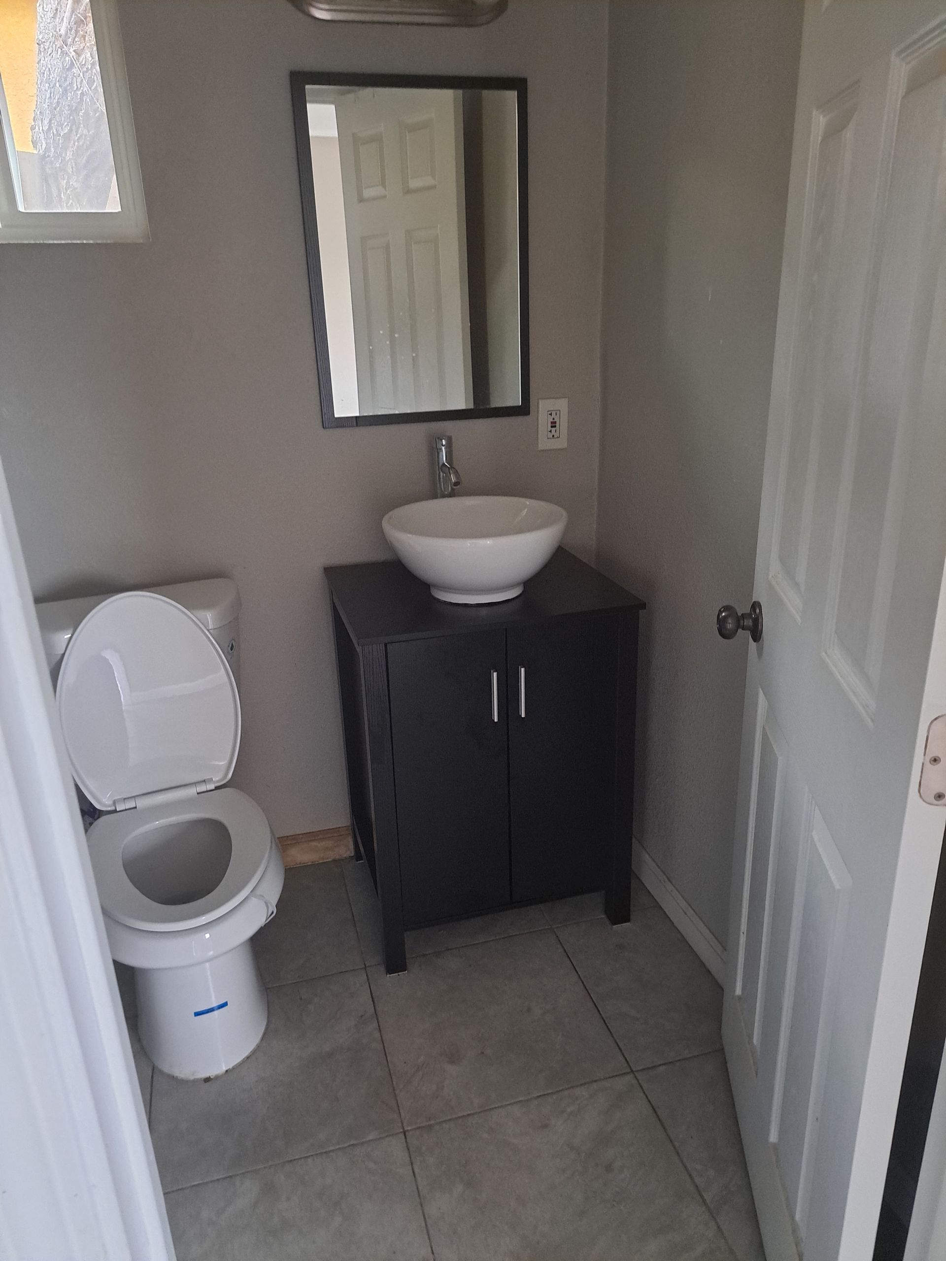 A bathroom with a toilet , sink and mirror