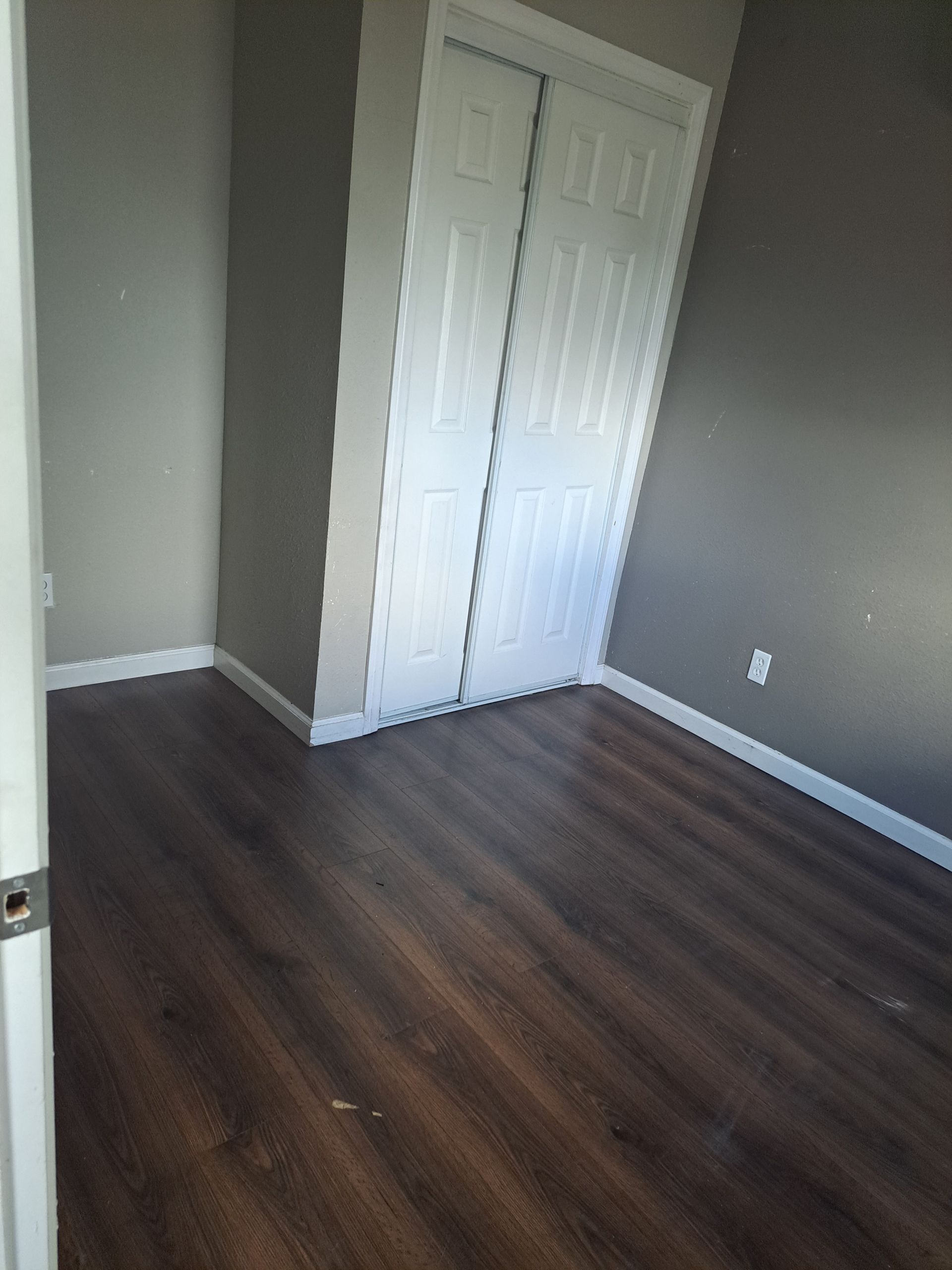 An empty room with hardwood floors and a closet.