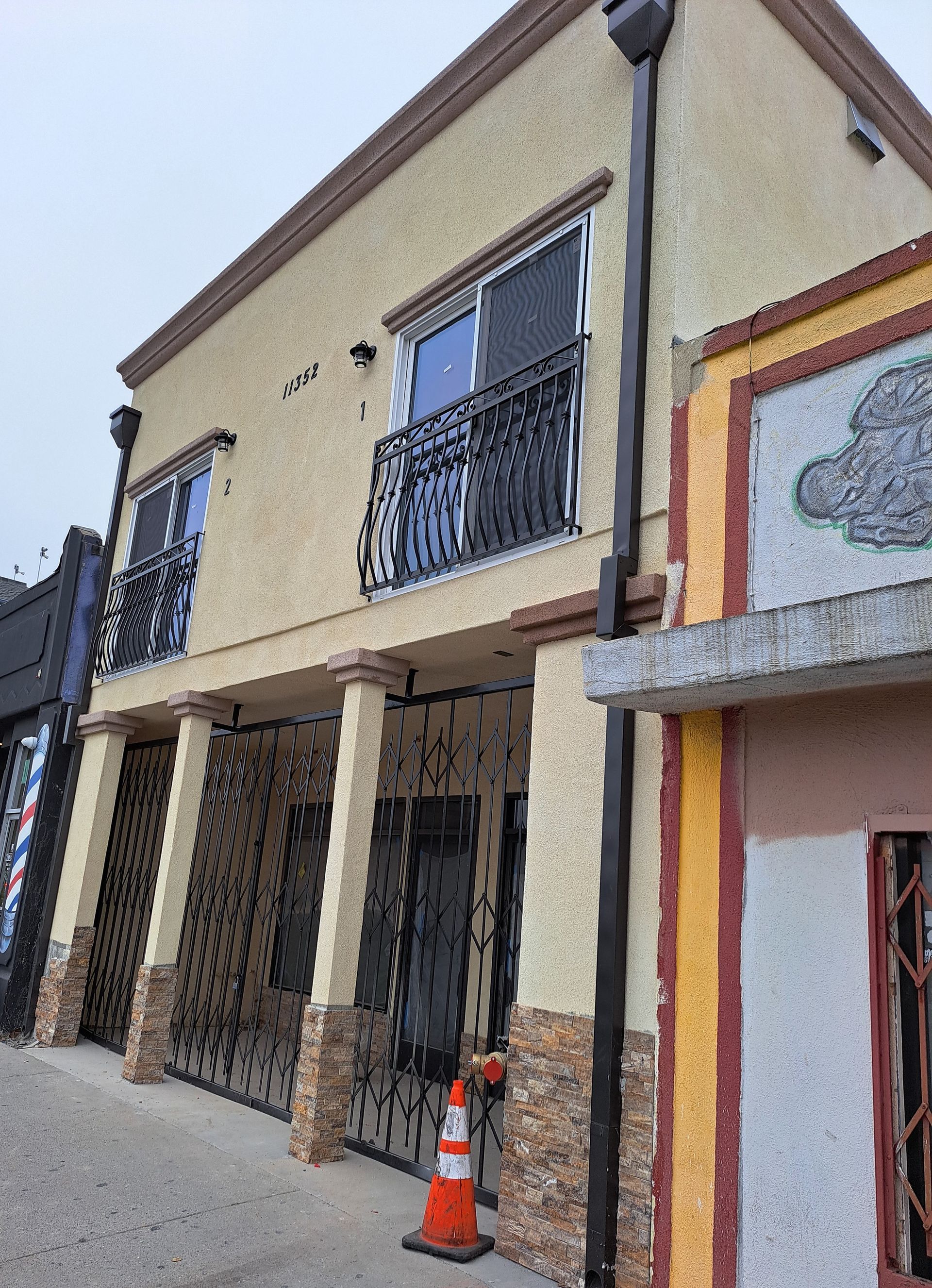 A building with a balcony and a sign that says ' barber shop ' on it.