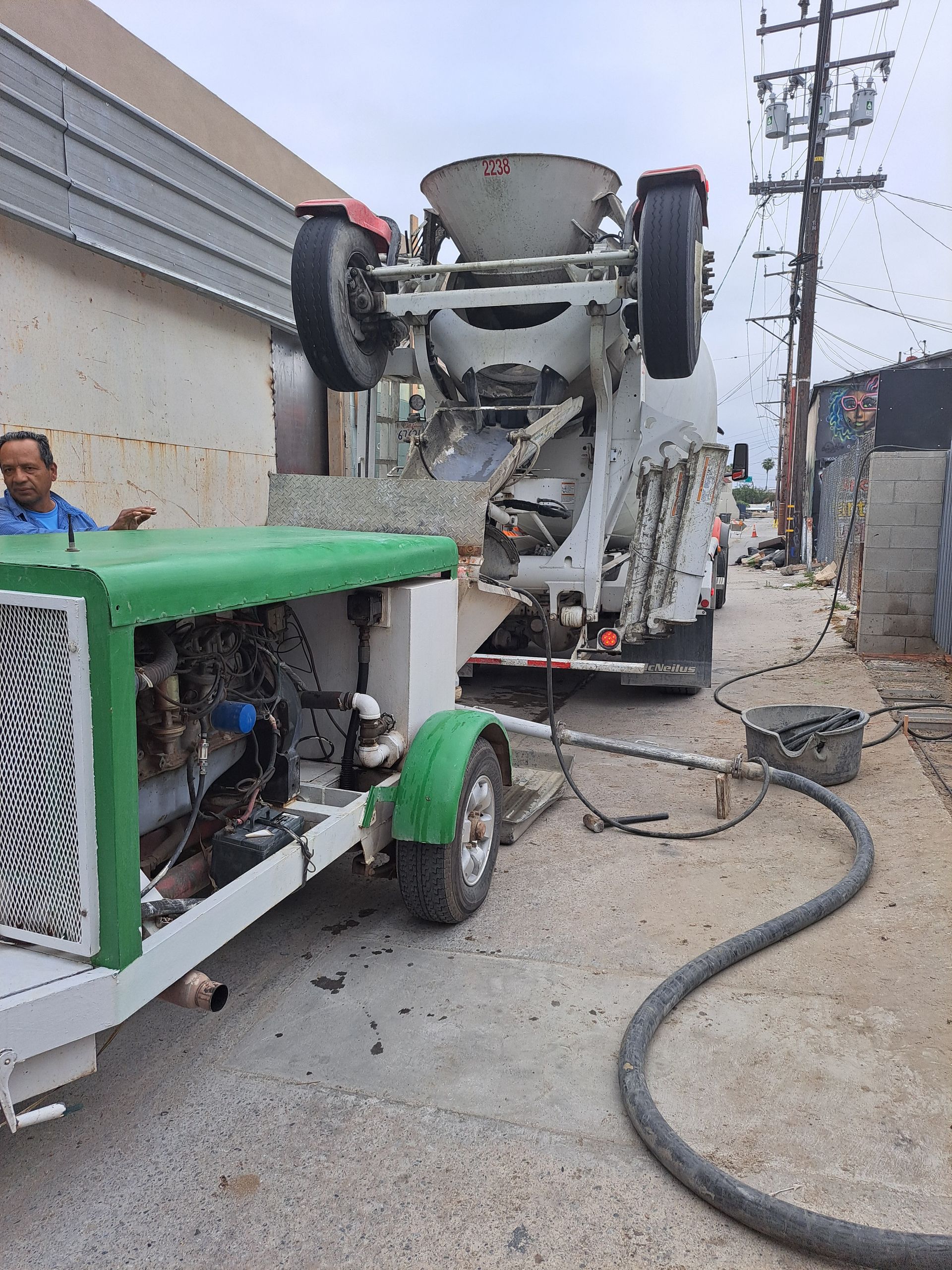 A man is standing next to a concrete mixer on a trailer.