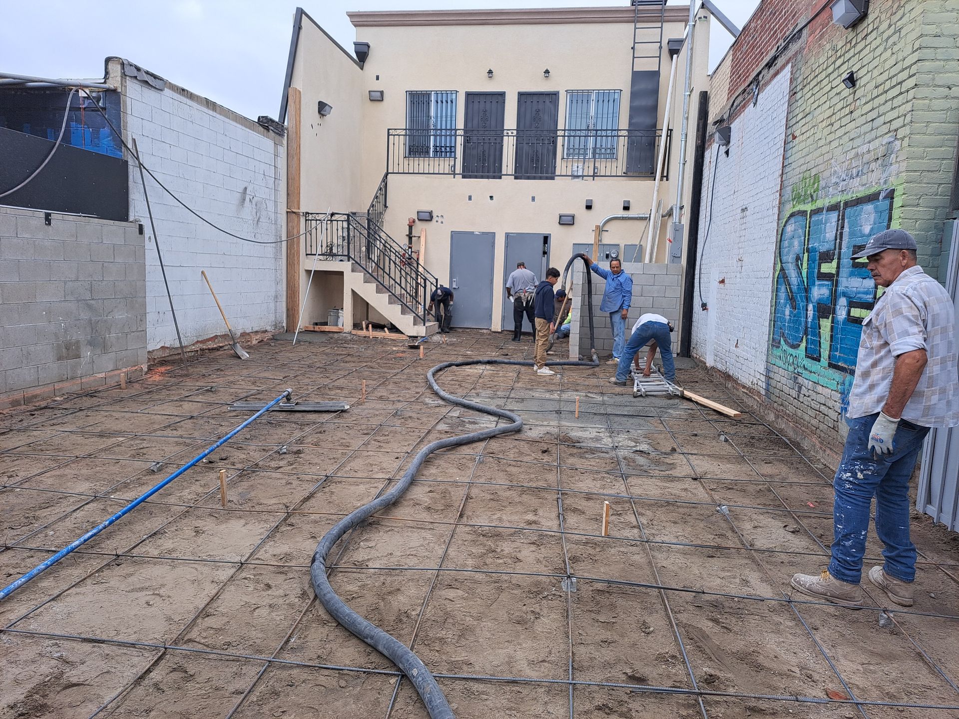 A group of men are working on a construction site in front of a building.