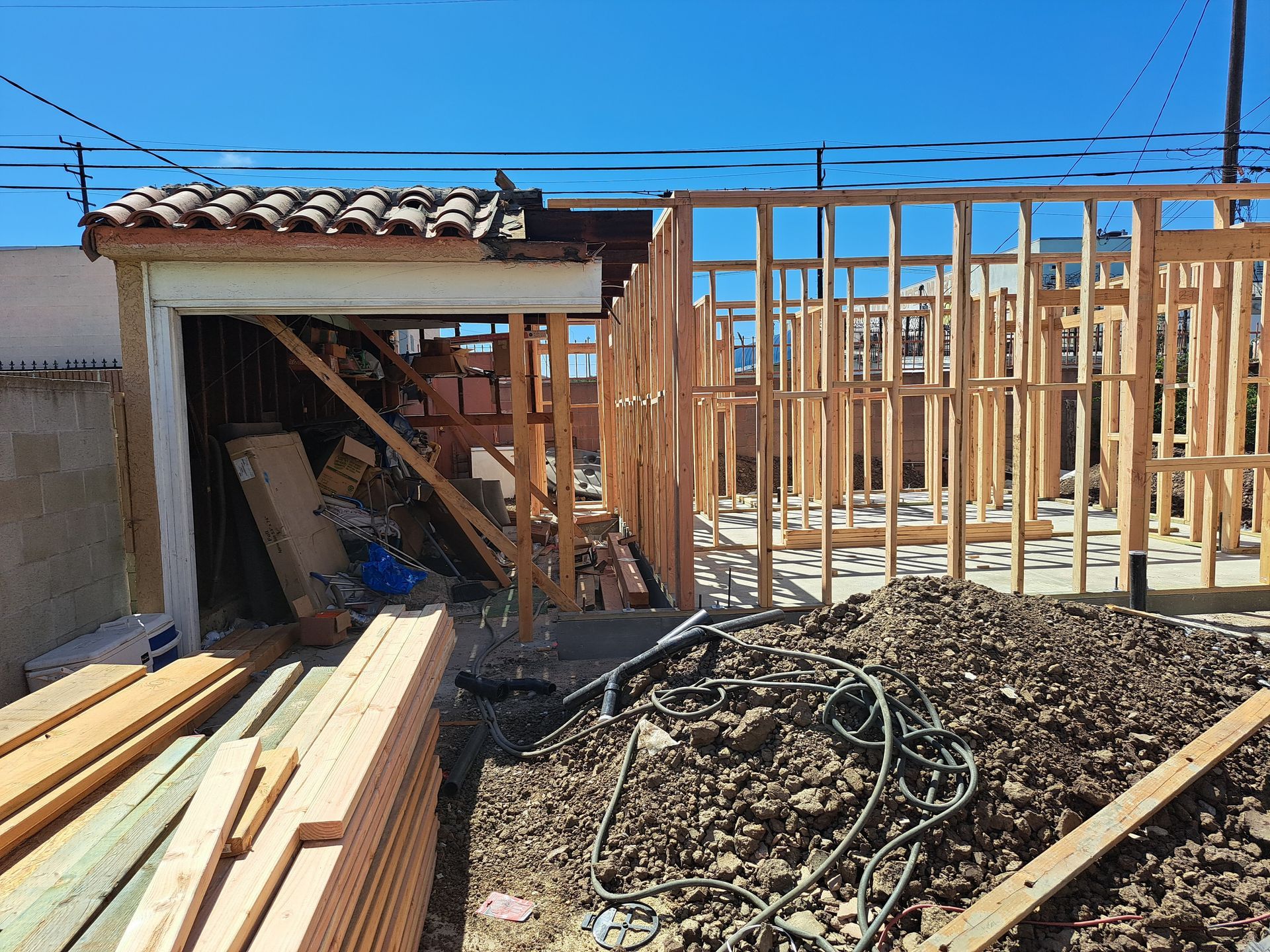 A house is being built and a pile of wood is in front of it.