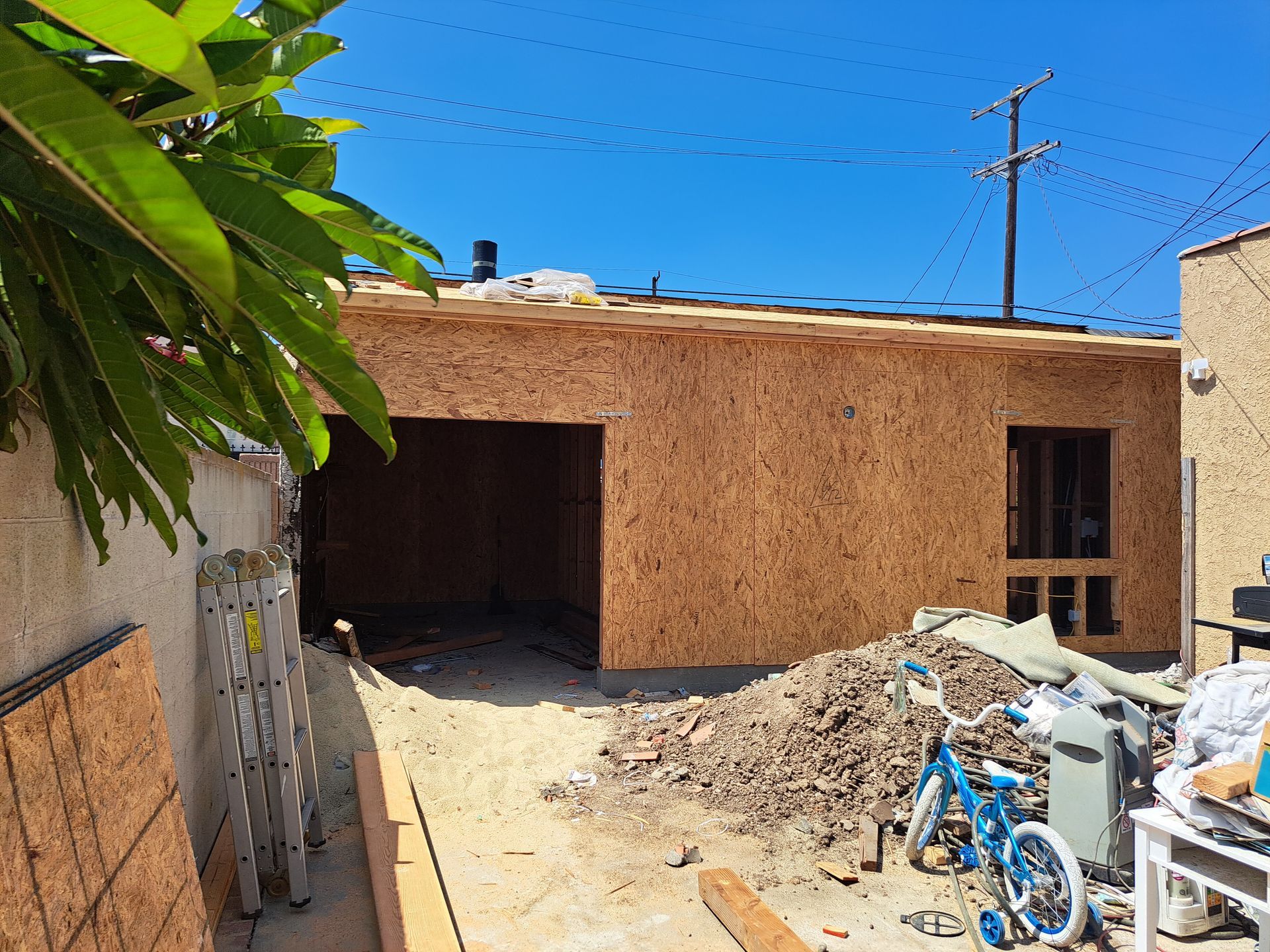 A bicycle is parked in front of a building under construction.