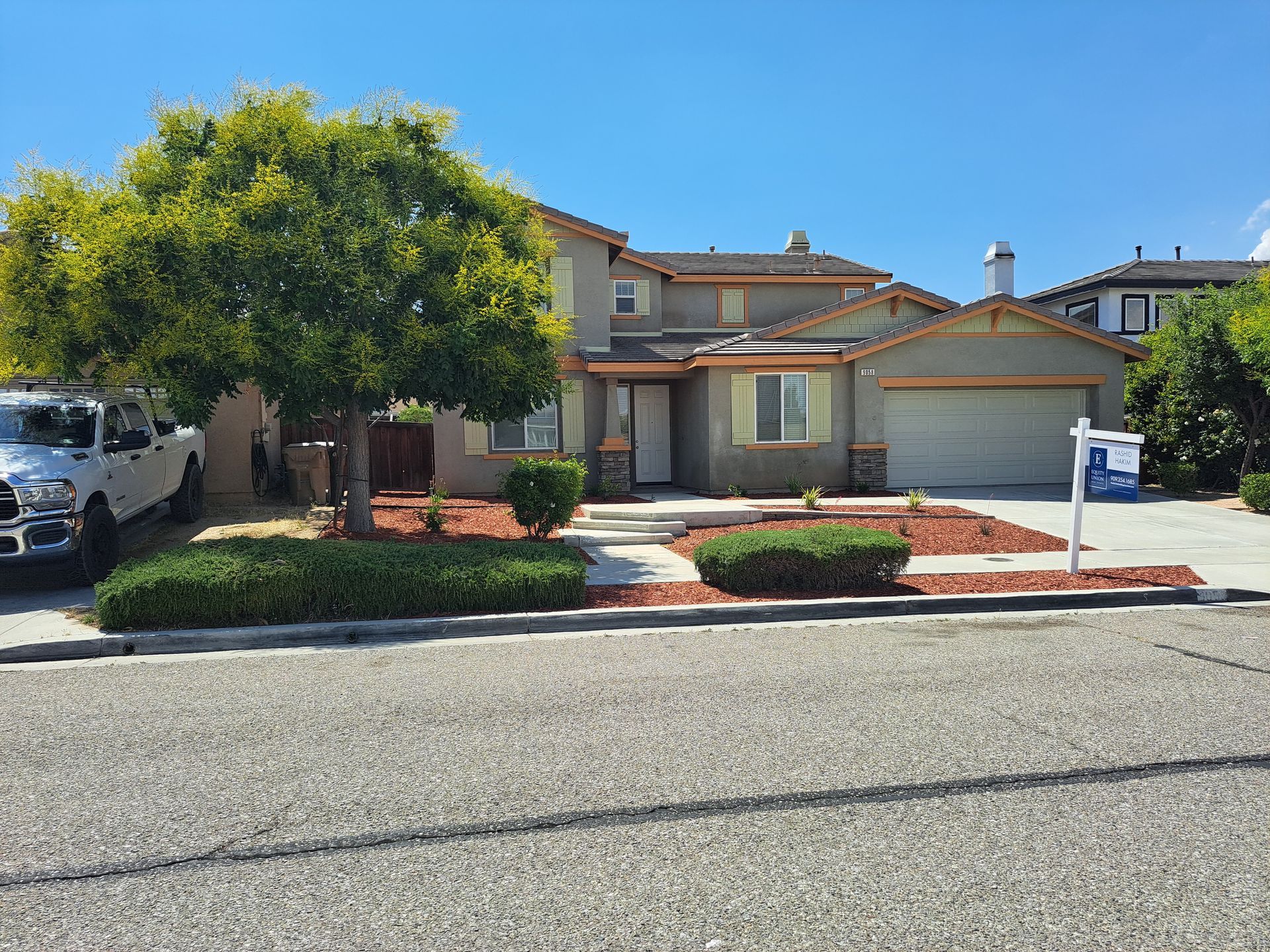 A white truck is parked in front of a house for sale.