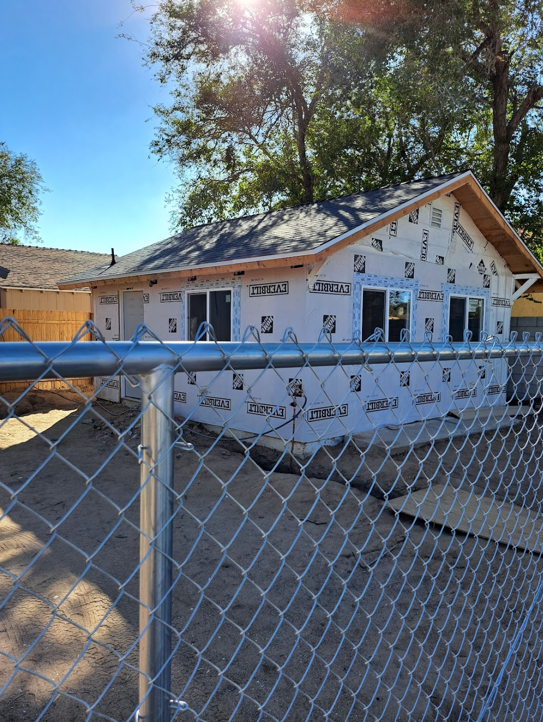 A chain link fence is surrounding a house under construction.