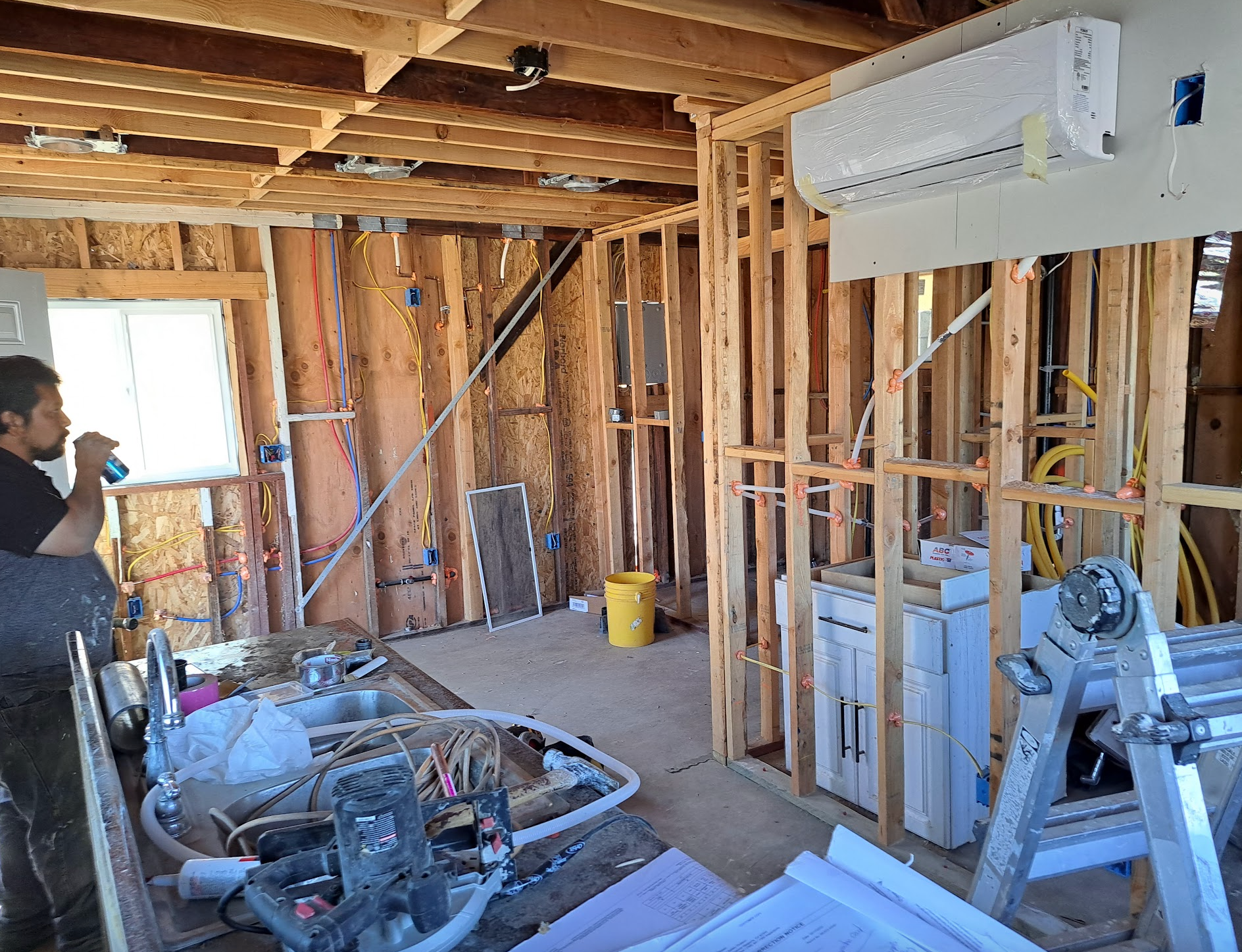 A man is drinking water in a room under construction.